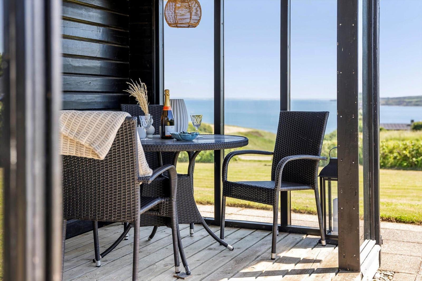 Terrasse mit Tisch und Stühlen, Blick auf das Meer.