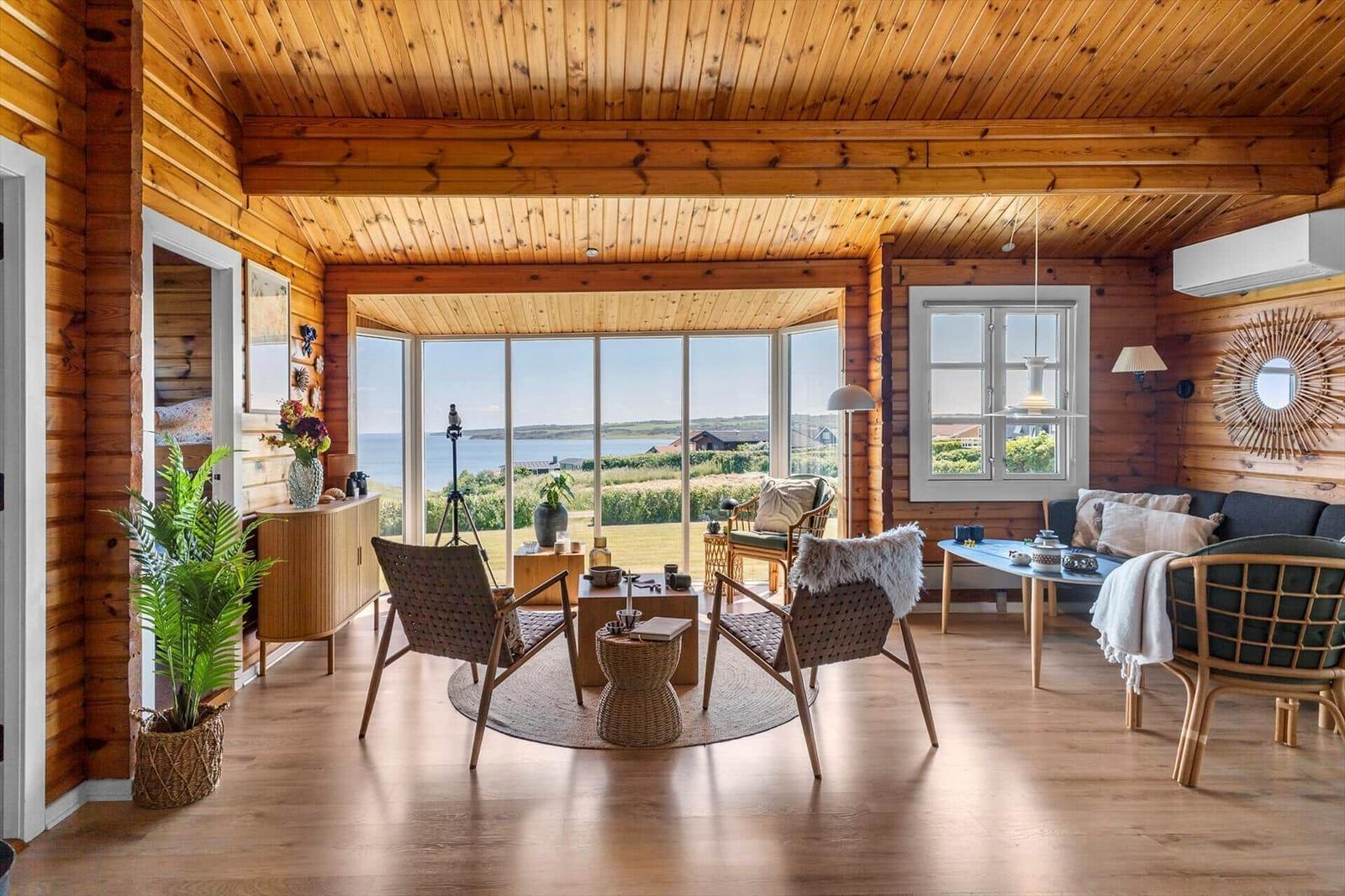 Wohnzimmer mit Holzdecke, Sitzgelegenheiten und Blick aufs Meer.