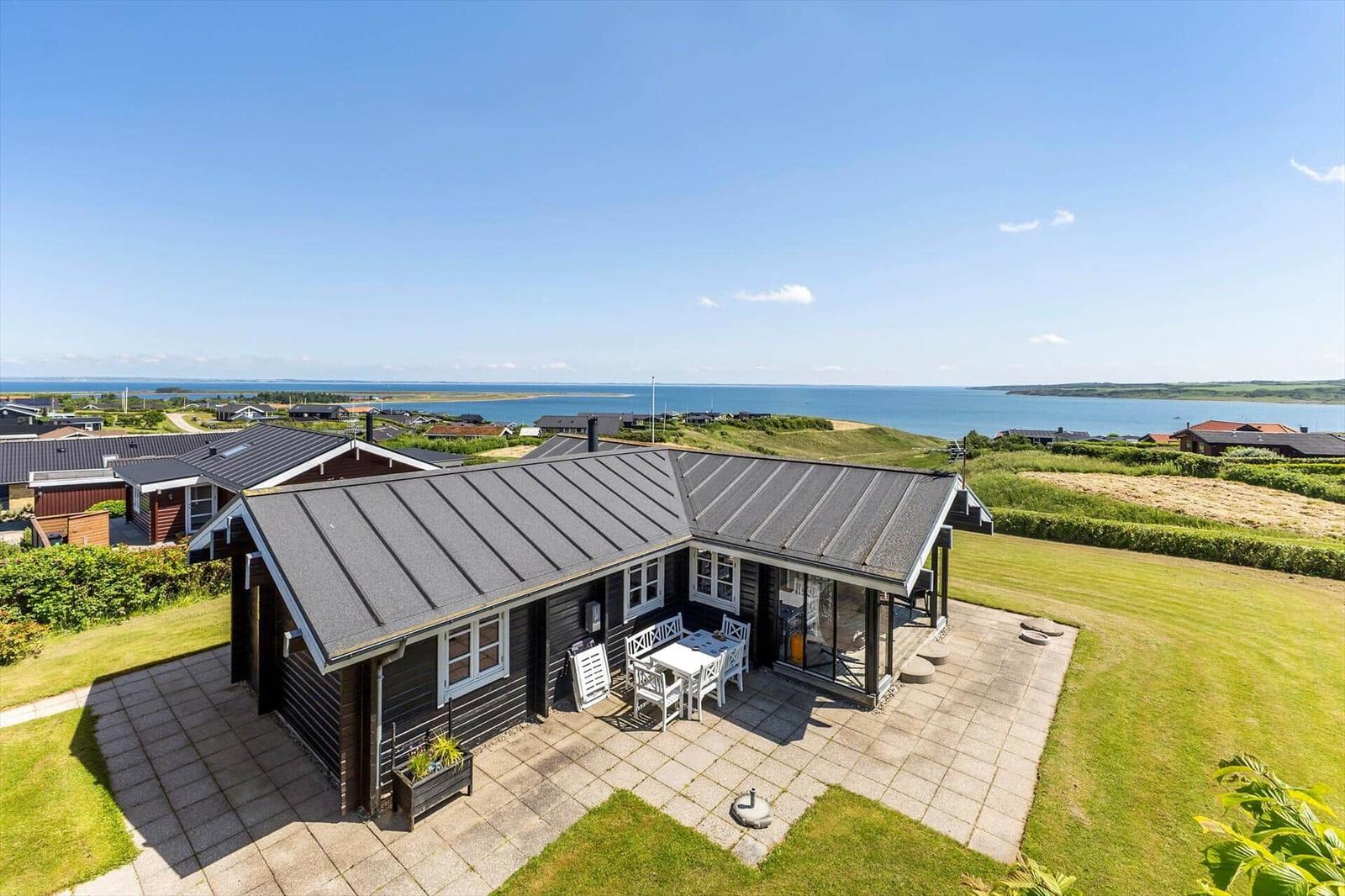 Modernes Haus mit Terrasse und Meerblick. Grünfläche und Blick auf Wasser.