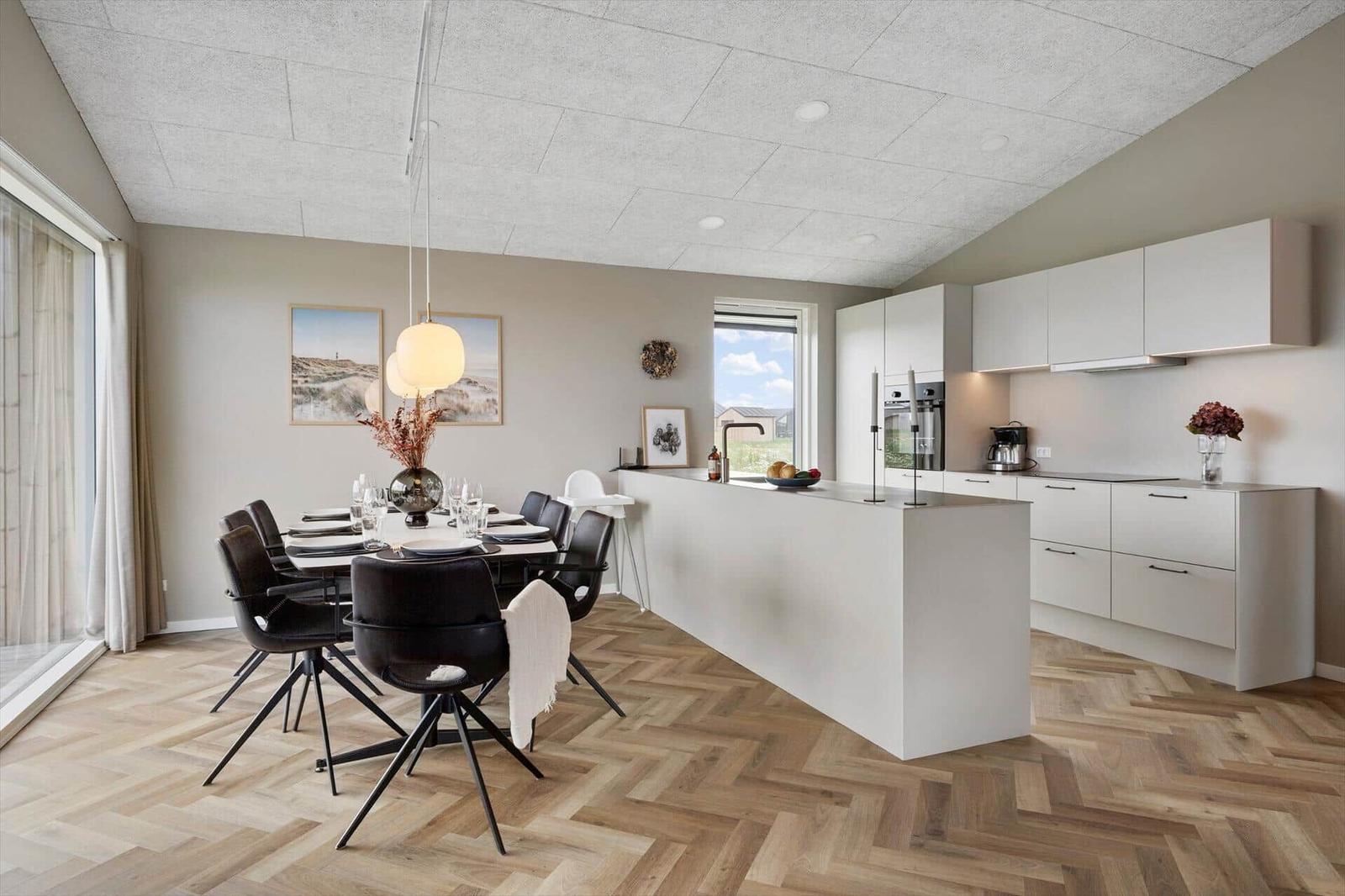 Moderne Küche mit Essbereich, weiße Schränke und Holzboden im Herringbone-Muster.