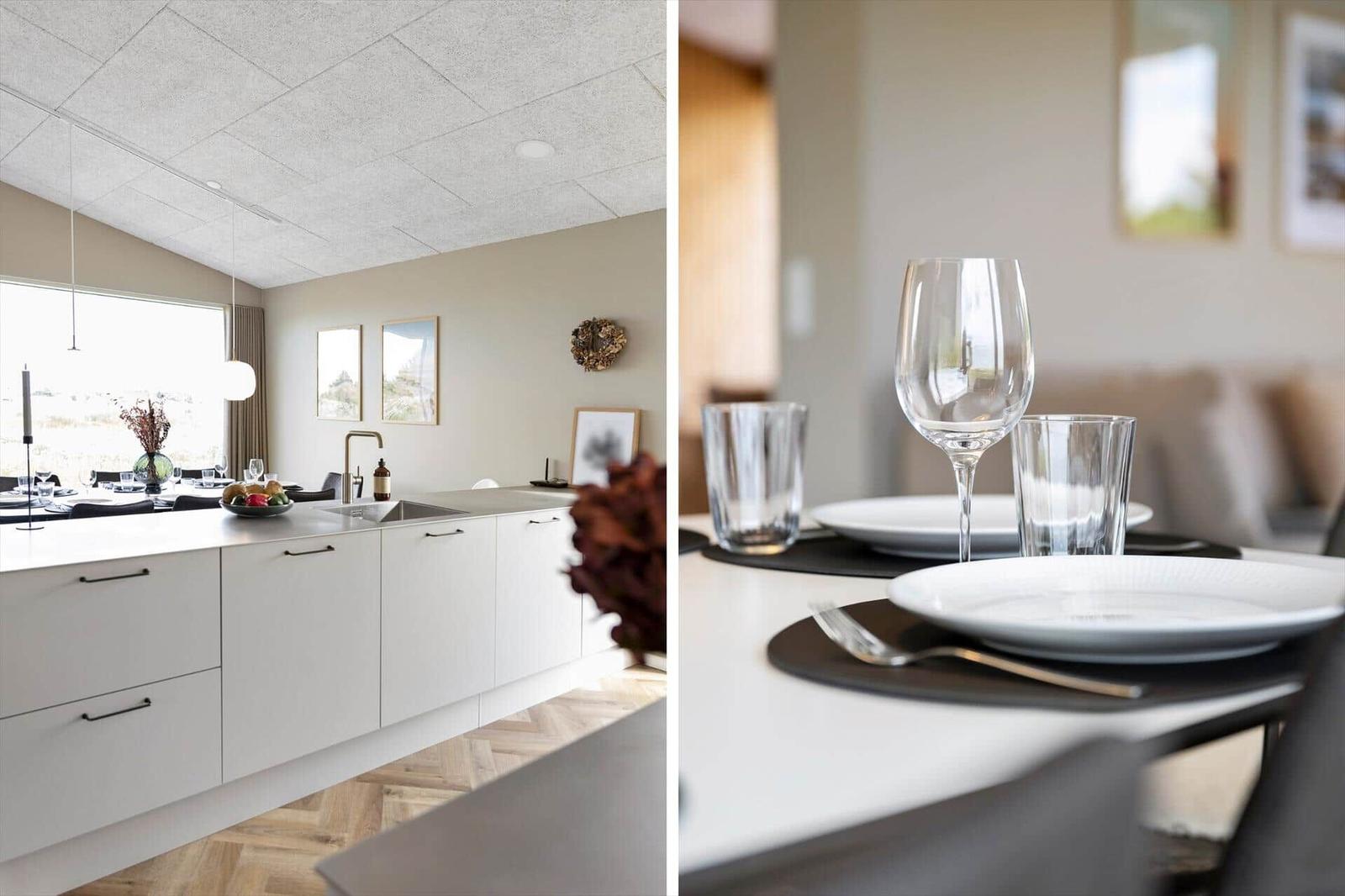 Moderne Küche mit Essbereich. Weiße Schränke, Holzboden und Tisch mit Geschirr.