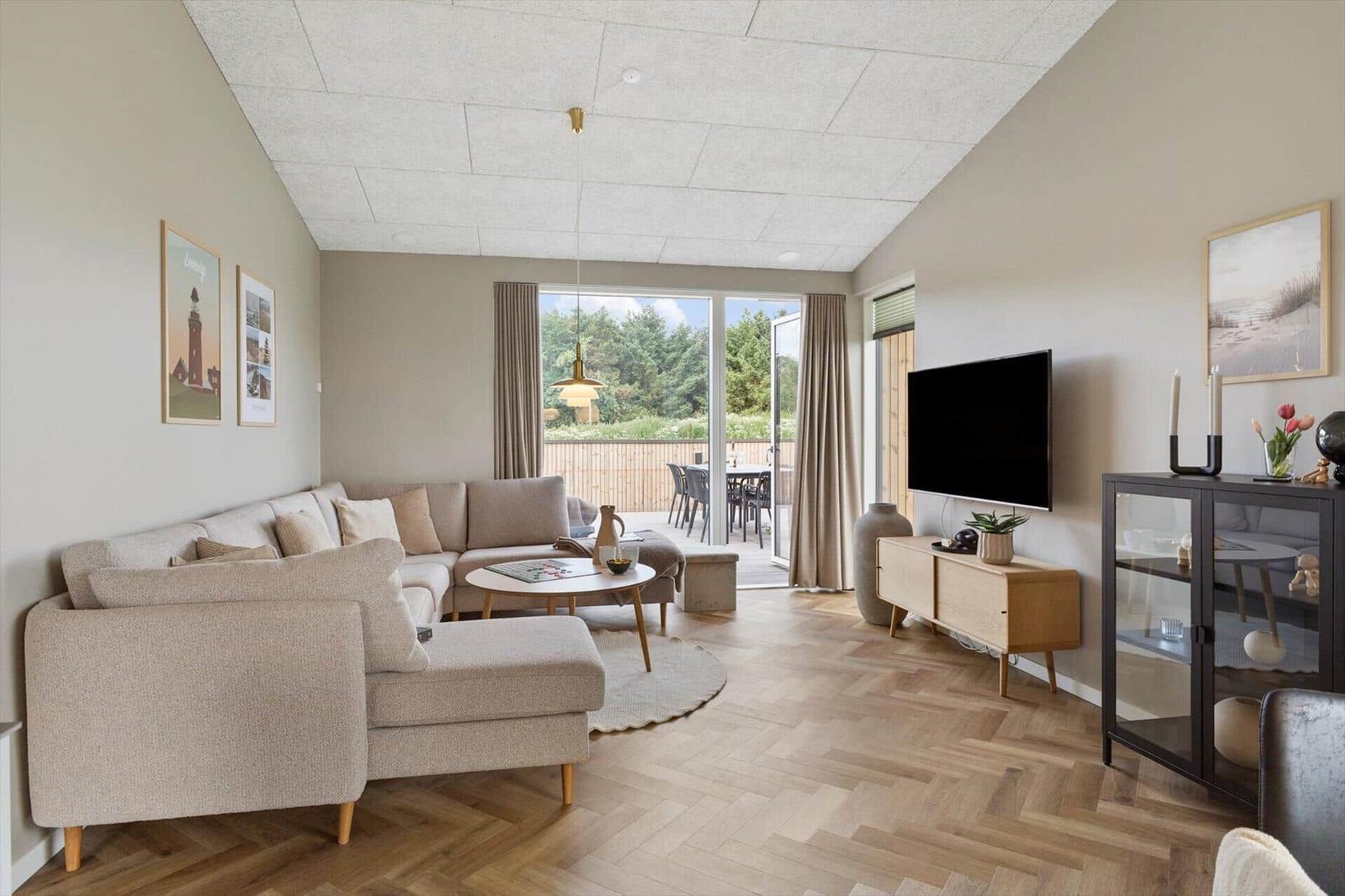 Wohnzimmer mit Sofa, Fernseher und Blick auf die Terrasse.