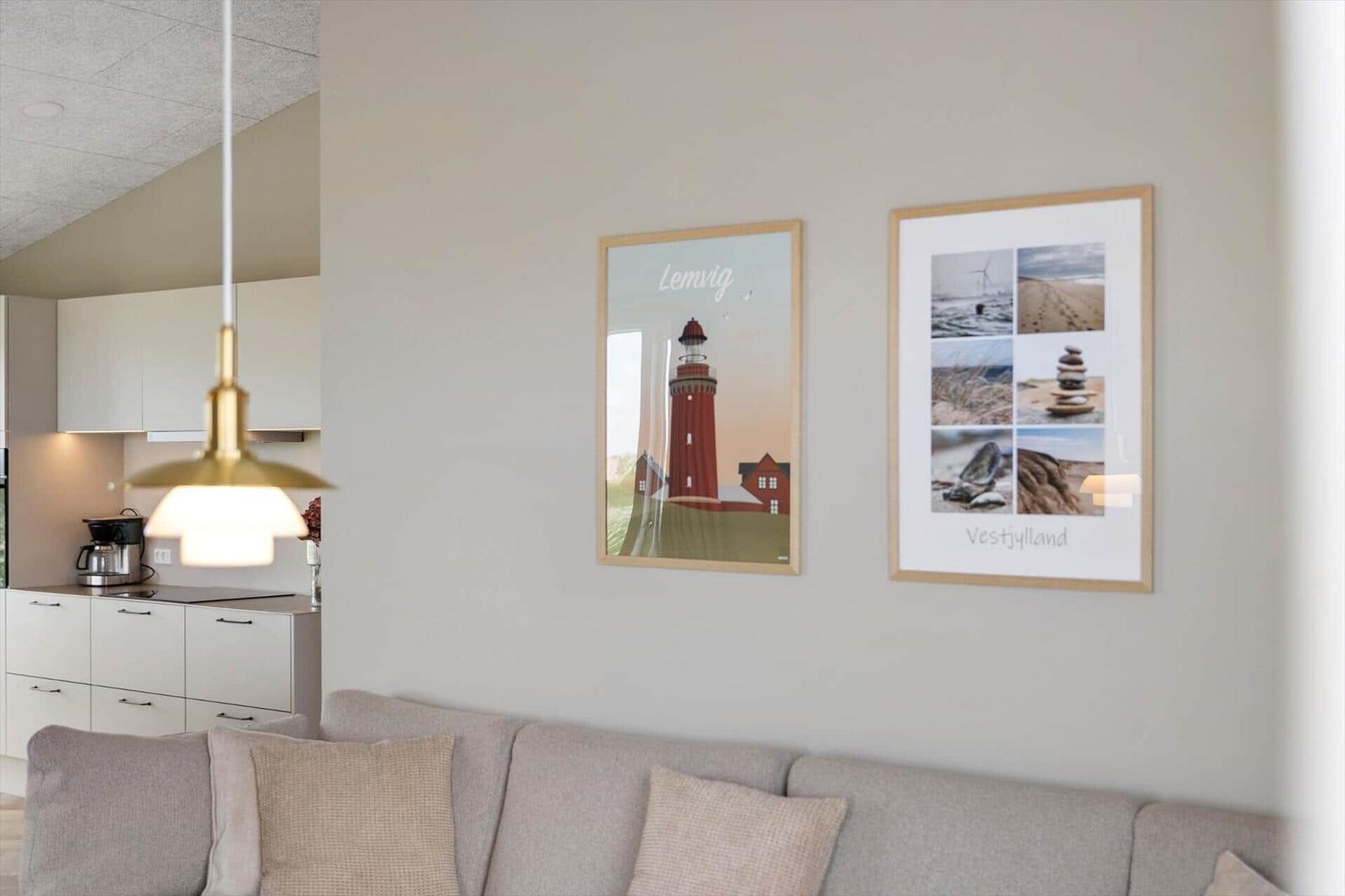 Wohnzimmer mit Sofa, Küchenbereich und Wandbildern von Lemvig und Vestjylland.