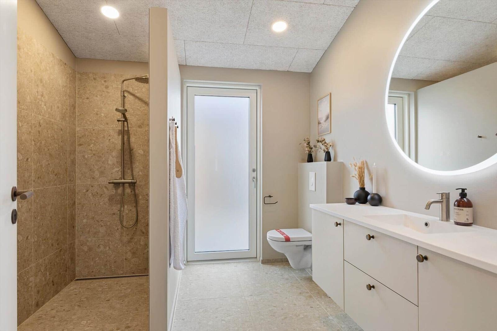 Badezimmer mit Dusche, Waschbecken und Toilette.