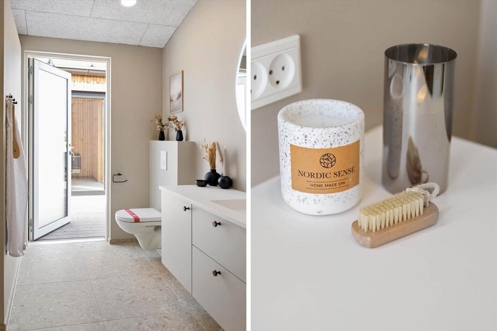 Badezimmer mit Toilette und Waschtisch. Auf der Arbeitsfläche steht eine Kerze und ein Bürstenhalter.
