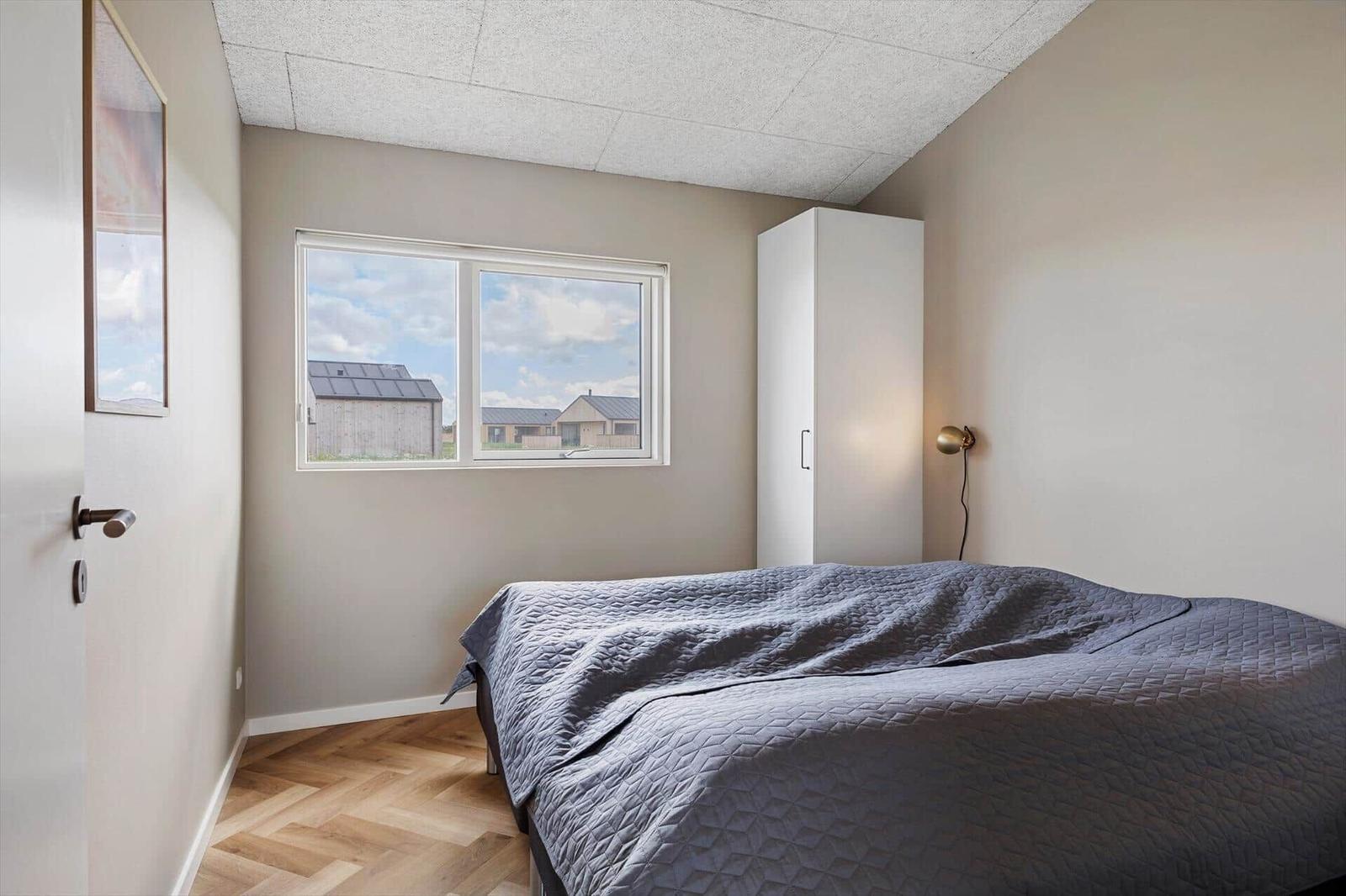 Schlafzimmer mit Bett, Fenster und Kleiderschrank.