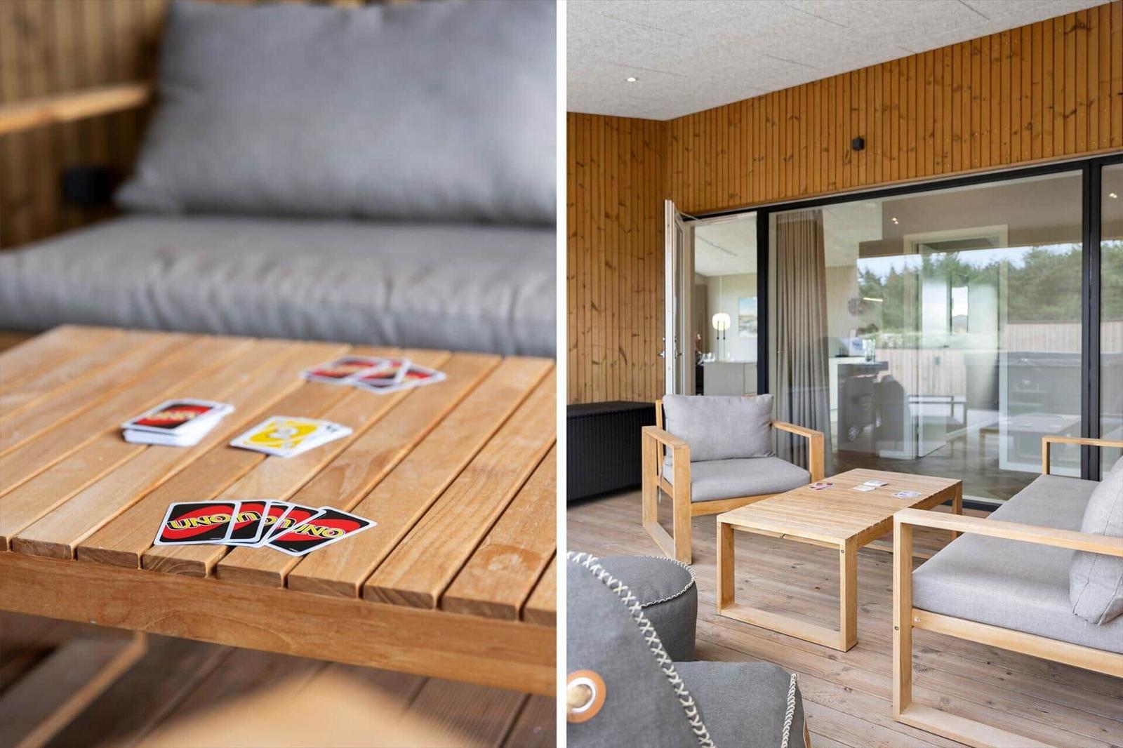 Holztisch mit Uno-Karten und graue Sitzgelegenheiten in einem Raum mit Holzwandverkleidung.