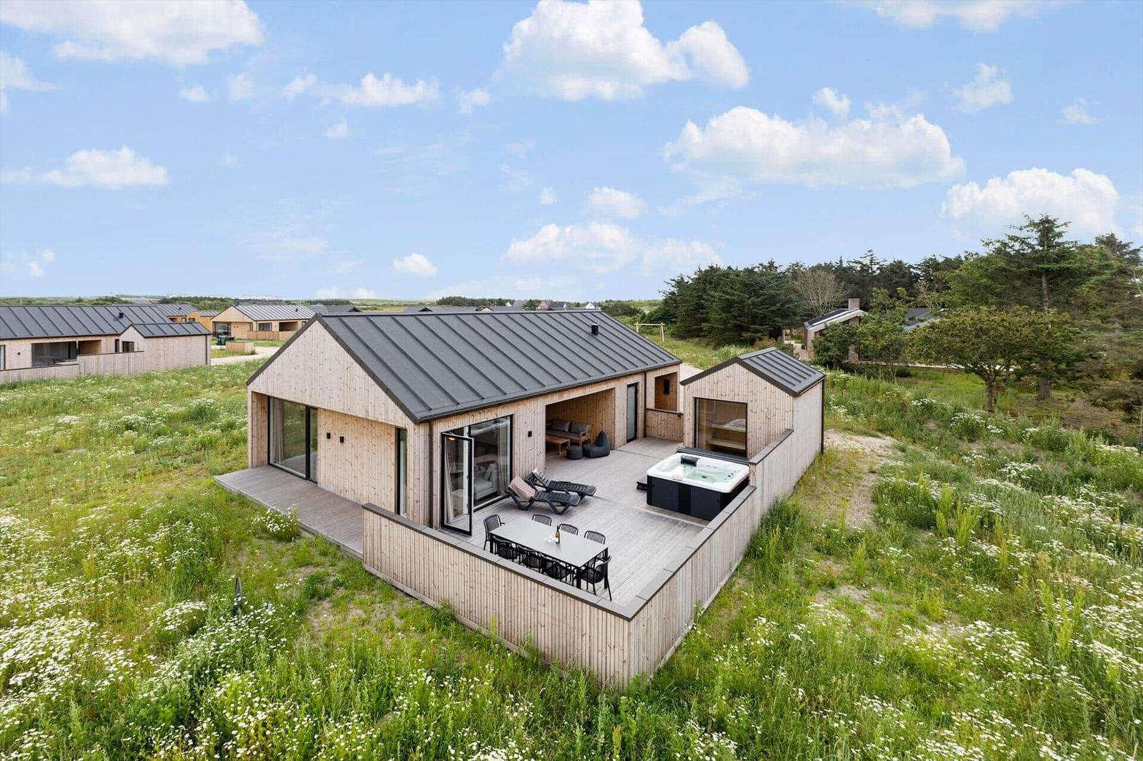 Moderne Holzhütte mit Terrasse, Whirlpool und Garten. Sicht auf weitere Unterkünfte.