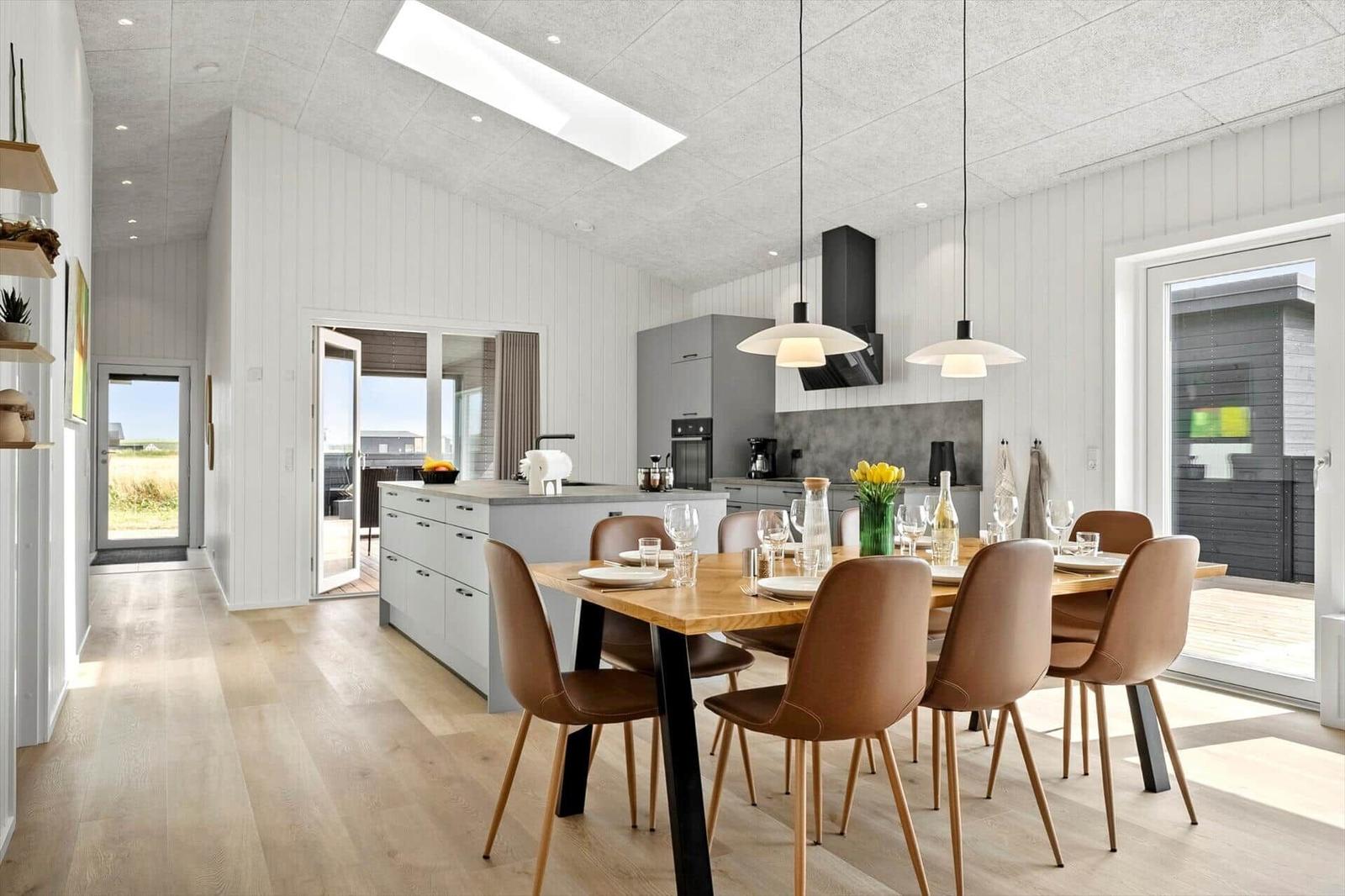 Moderne Küche mit Essbereich, Holzboden und großen Fenstern.