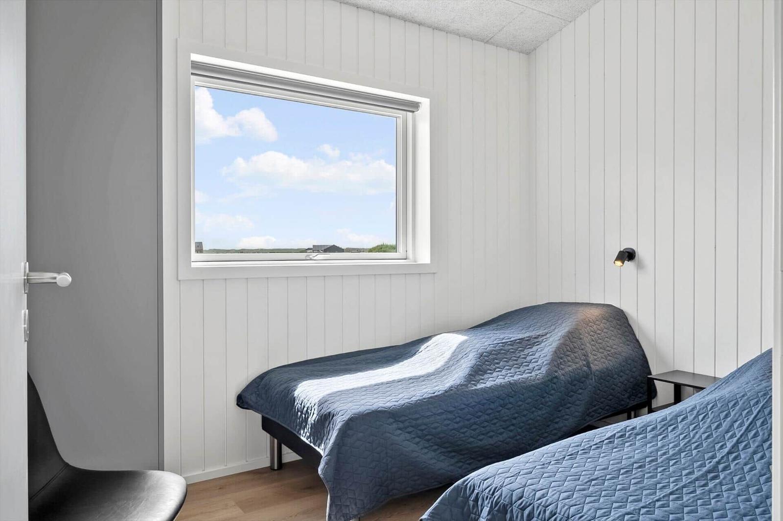 Zimmer mit zwei Betten, Fensterblick und Wandlampe.
