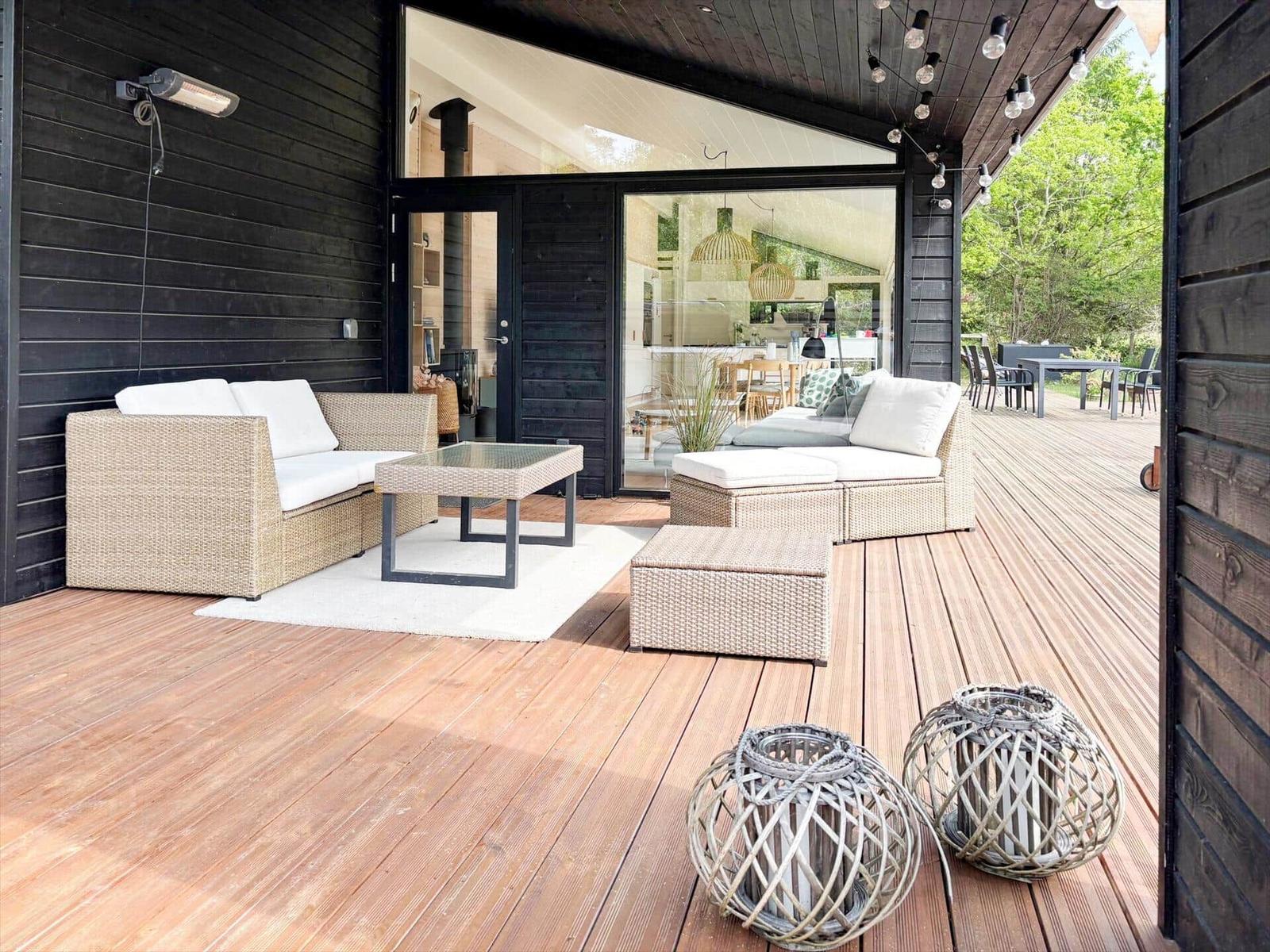 Terrasse mit Gartenmöbeln, Holzdecke und Blick ins Haus.
