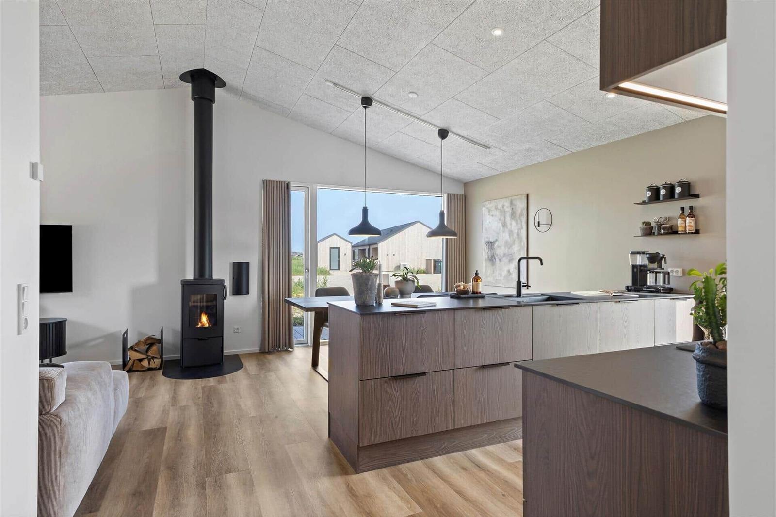 Moderne Küche mit Holzoberflächen und integriertem Kamin im Wohnbereich.