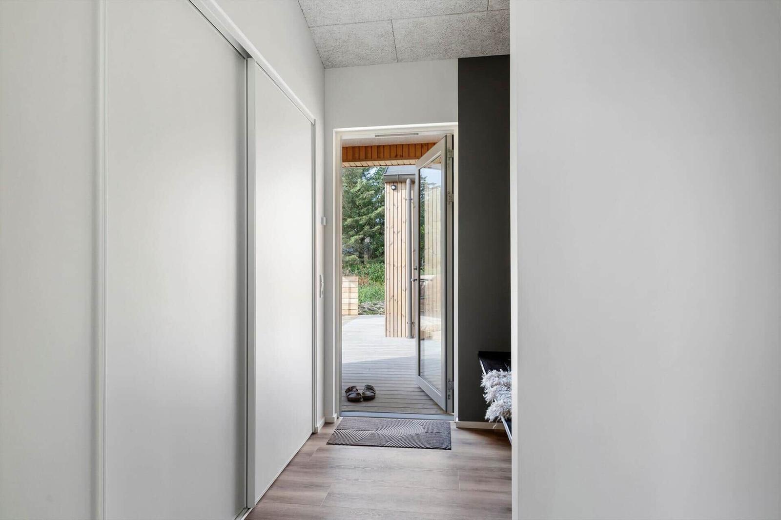 Hallenraum mit Schiebetüren und Tür zum Außenbereich mit Holzterrasse.