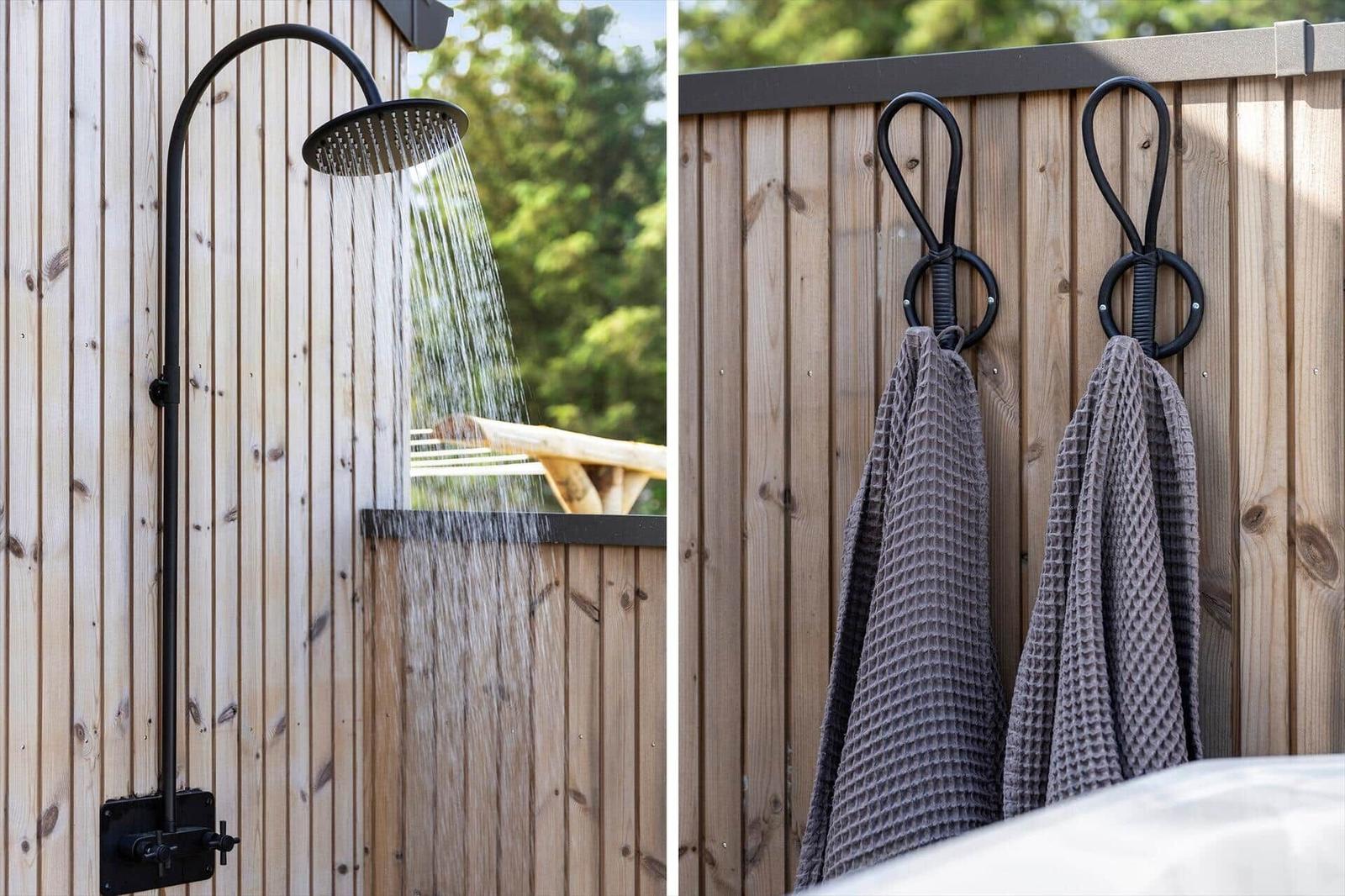 Außen-Dusche mit Wasserstrahl und Handtuchhalter an Holzwand.