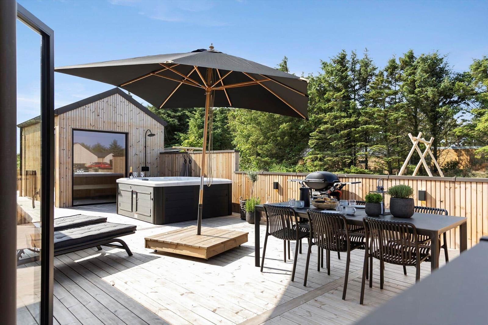 Terrasse mit Hot tub, Grill und Sitzgruppe unter Sonnenschutz.