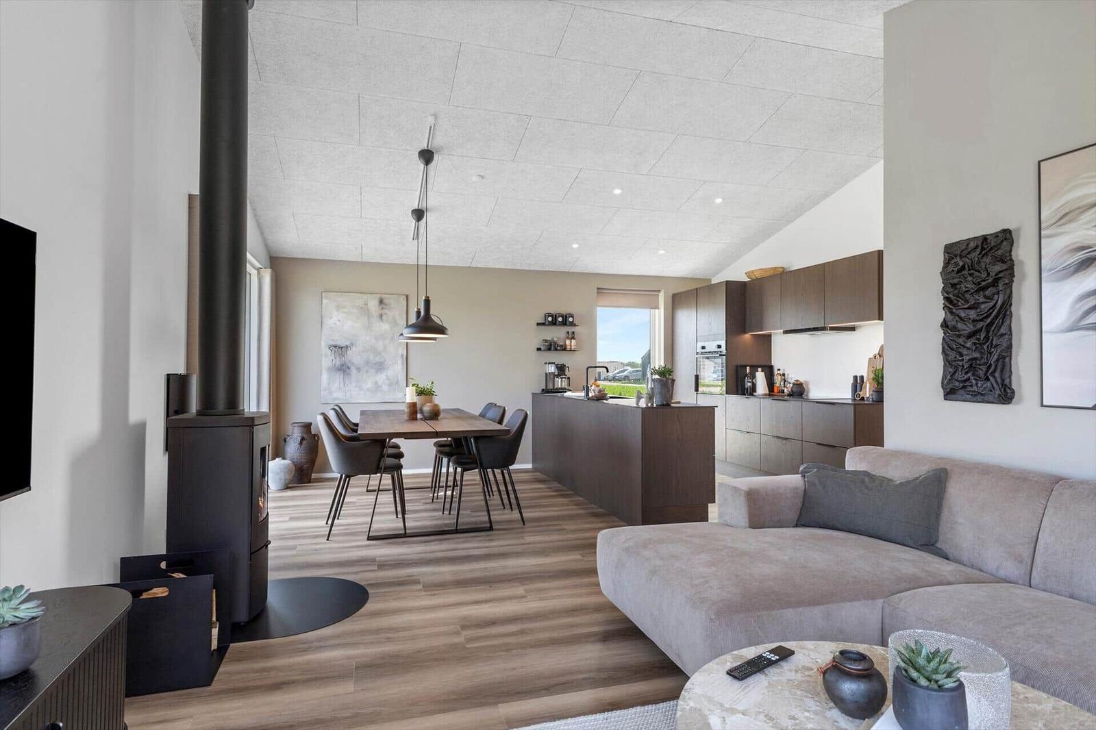 Wohn- und Essbereich mit Küche, Sofa und Kaminofen. Holzfußboden und moderne Einrichtung.