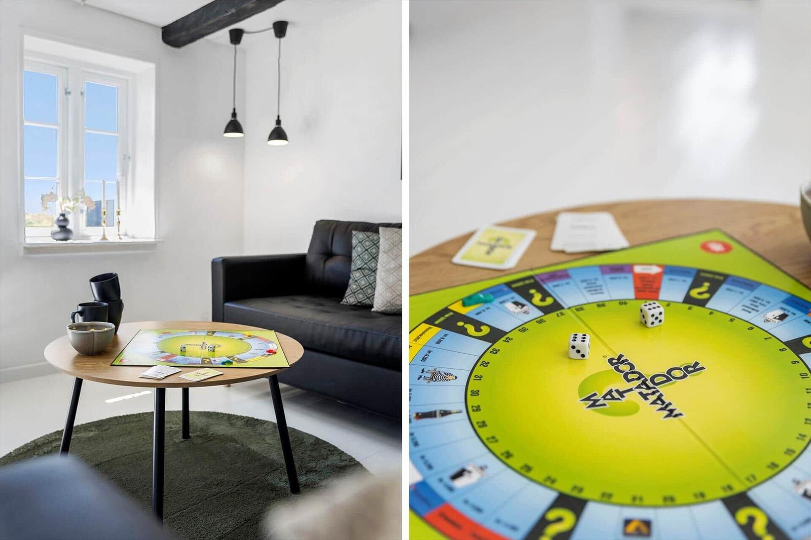Wohnzimmer mit Sofa, Tisch und Spiel. Spielbrett und Würfel auf Tisch.