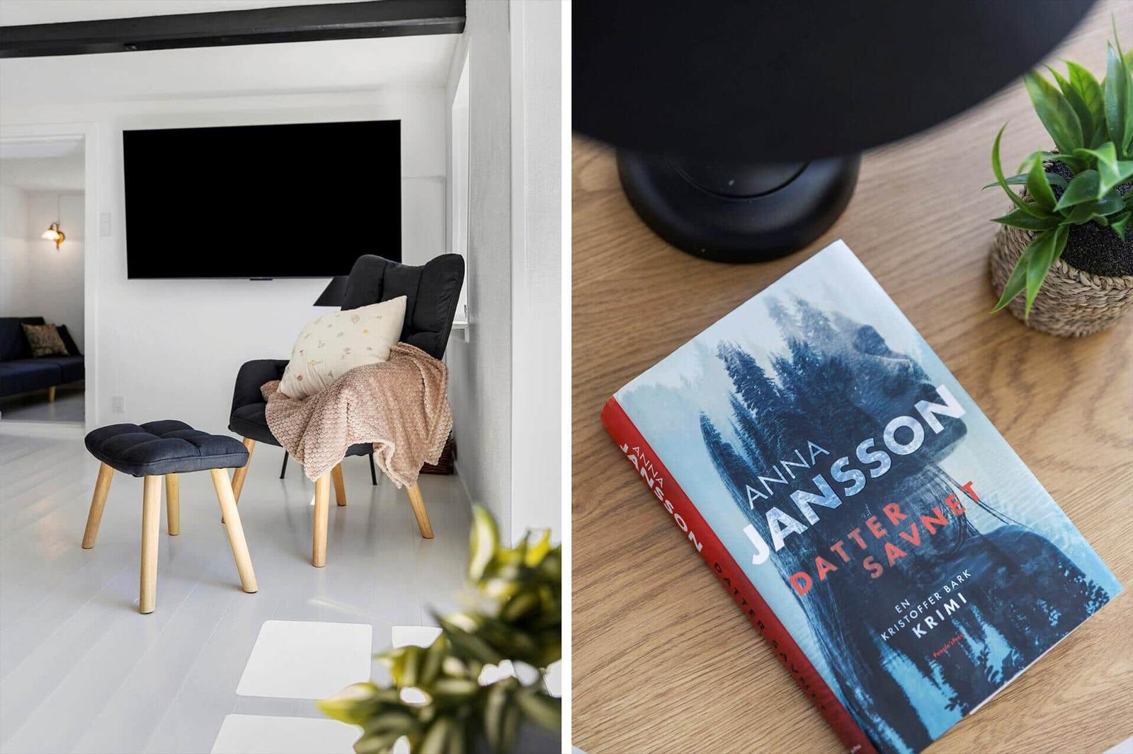 Ein Wohnzimmer mit Fernseher und Sessel. Ein Buch liegt auf einem Holztisch.