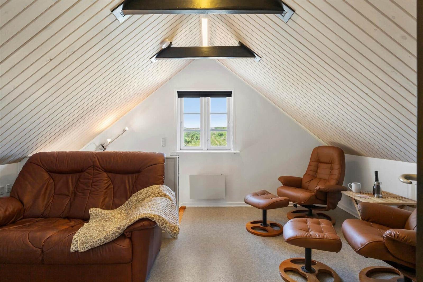 Dachgeschosszimmer mit braunen Ledermöbeln und schrägem Dach