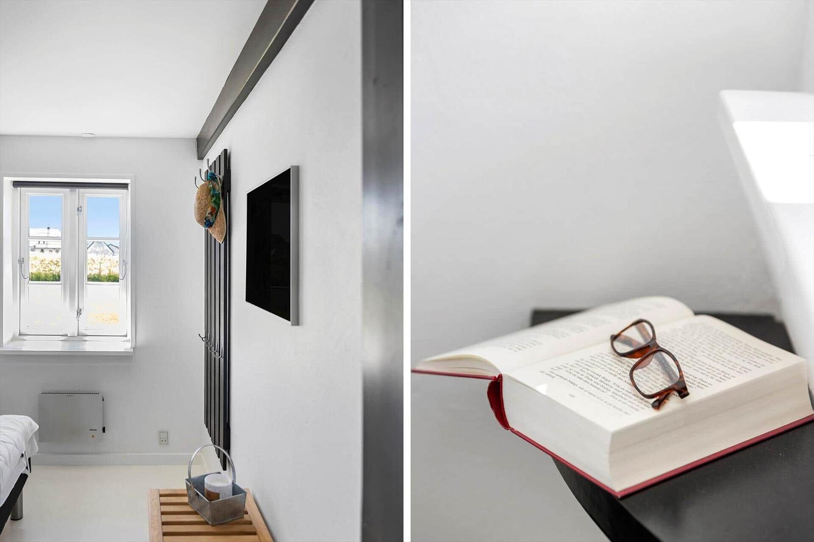 Zimmer mit Fenster und TV. Offener Buch mit Brille auf Tisch.