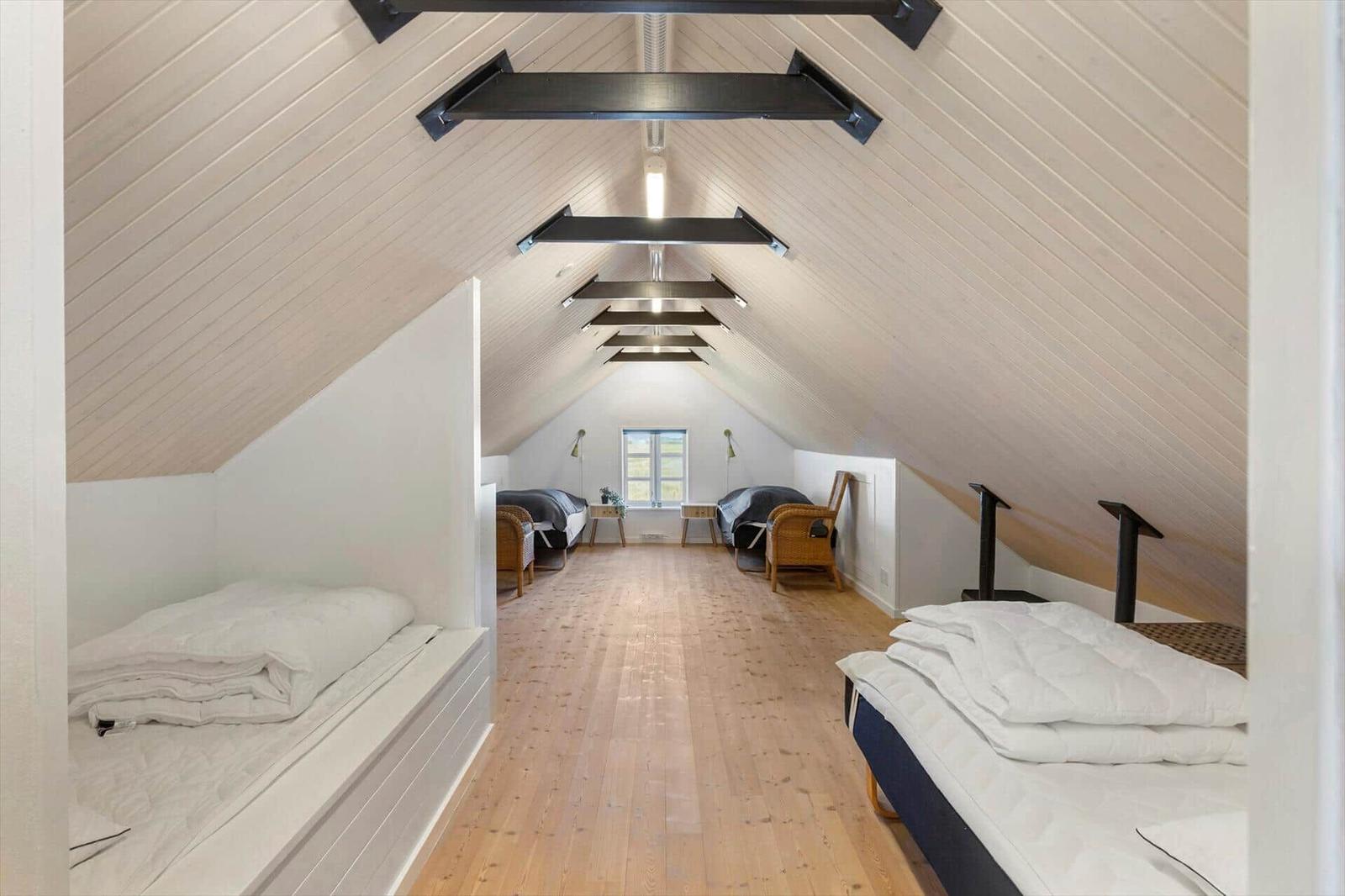 Dachgeschosszimmer mit Holzboden und mehreren Betten.