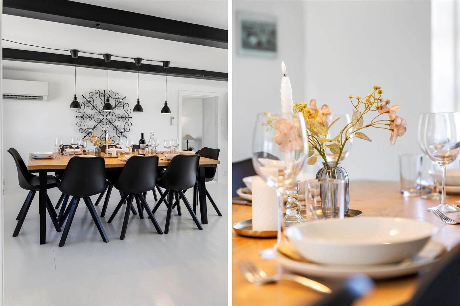 Esszimmer mit Holztisch, schwarzen Stühlen und hängenden Lampen. Tischdekoration mit Kerze und Blumen.