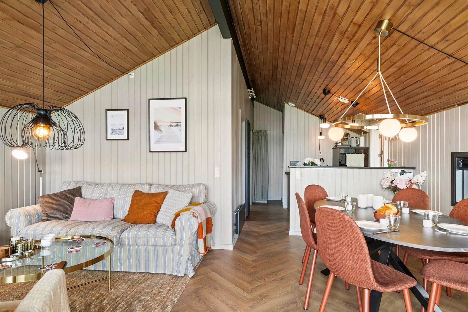Wohn- und Essbereich mit Sofa, Tisch und Stühlen unter Holzdecke.