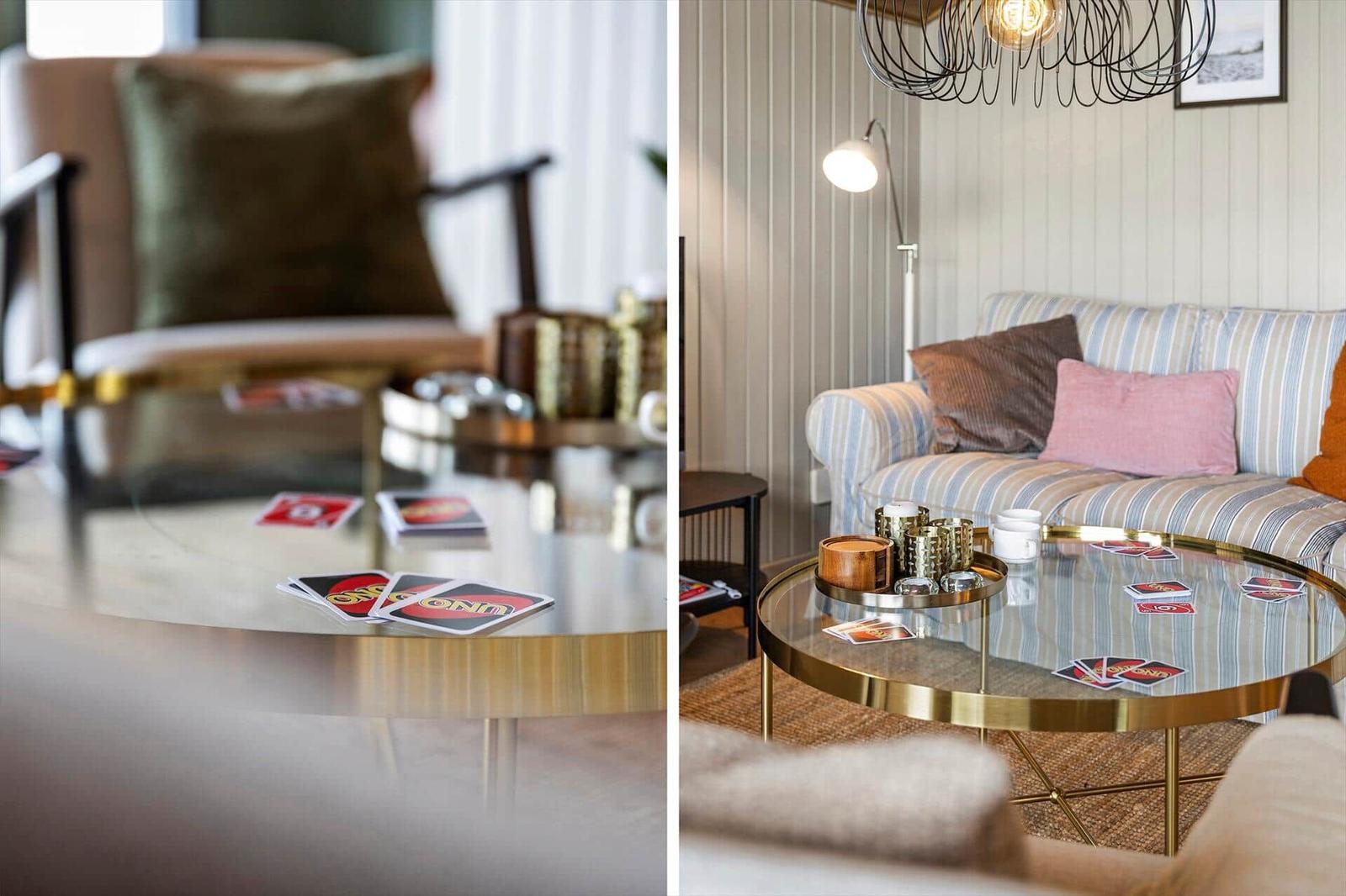 Glas-Tisch mit UNO-Karten und dekorativen Gegenständen vor einem Sofa mit Kissen.