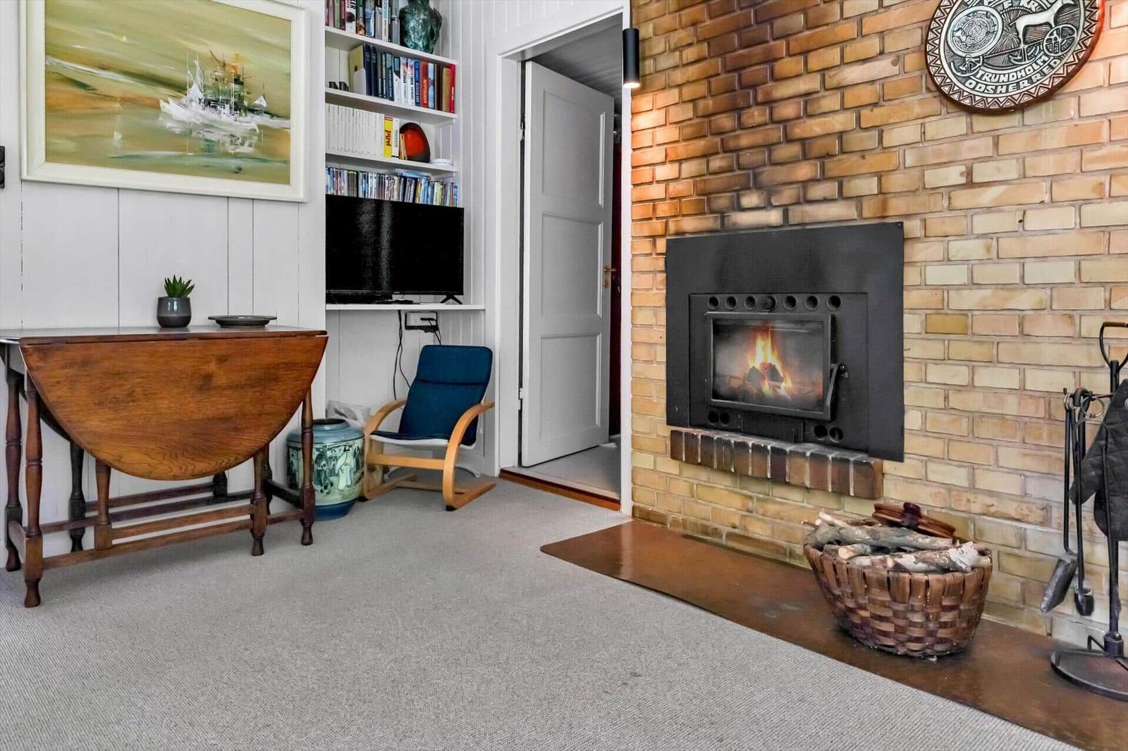 Raum mit Kamin, Fernseher, Bücherregal und Holztisch.