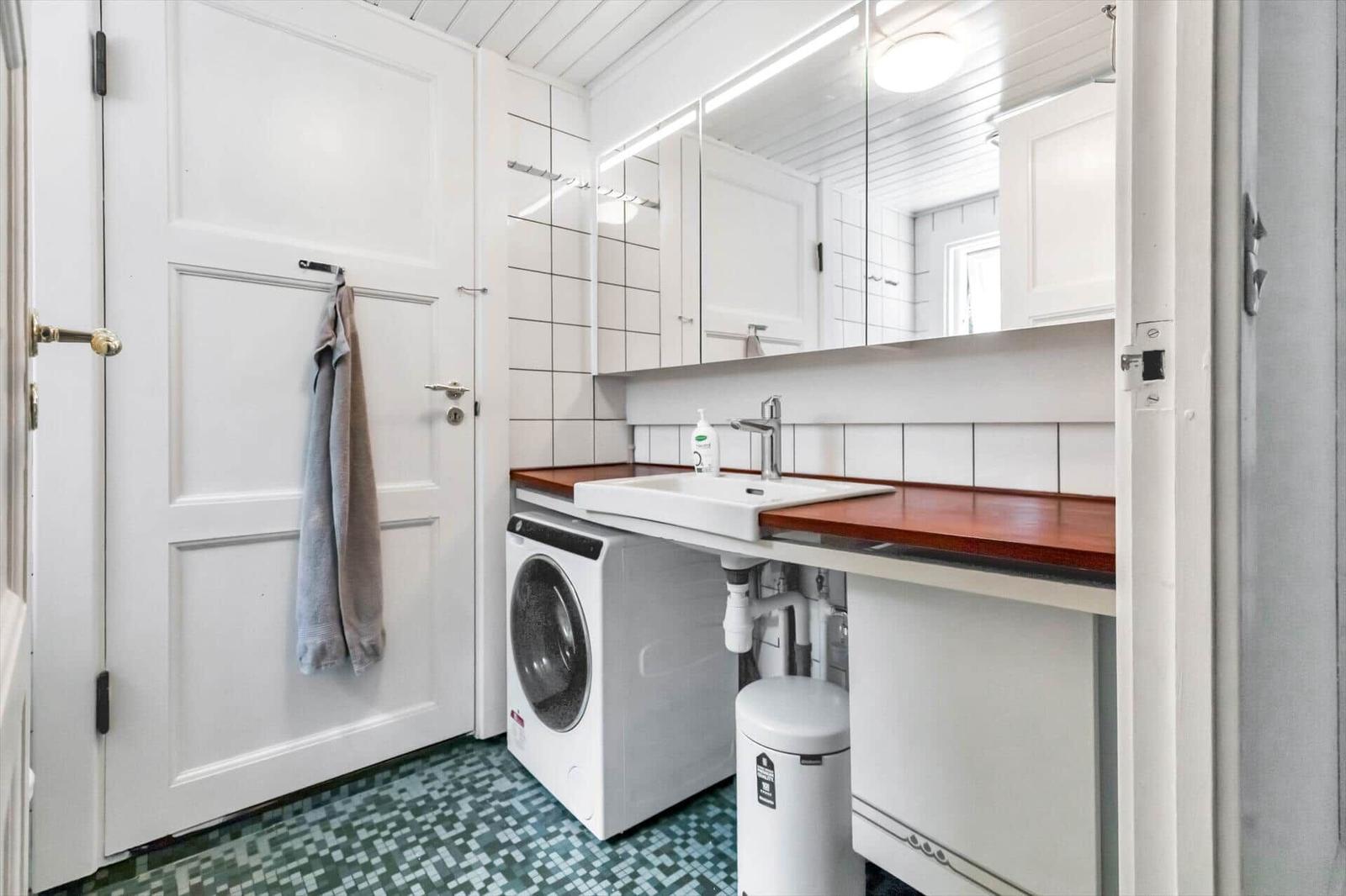 Badezimmer mit Waschmaschine, Spiegel und Holzoberfläche