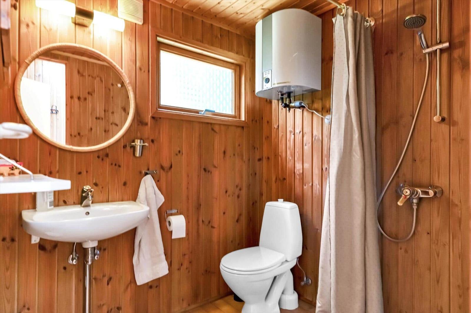 Bad mit Dusche, Toilette und Waschbecken an Holzwand.