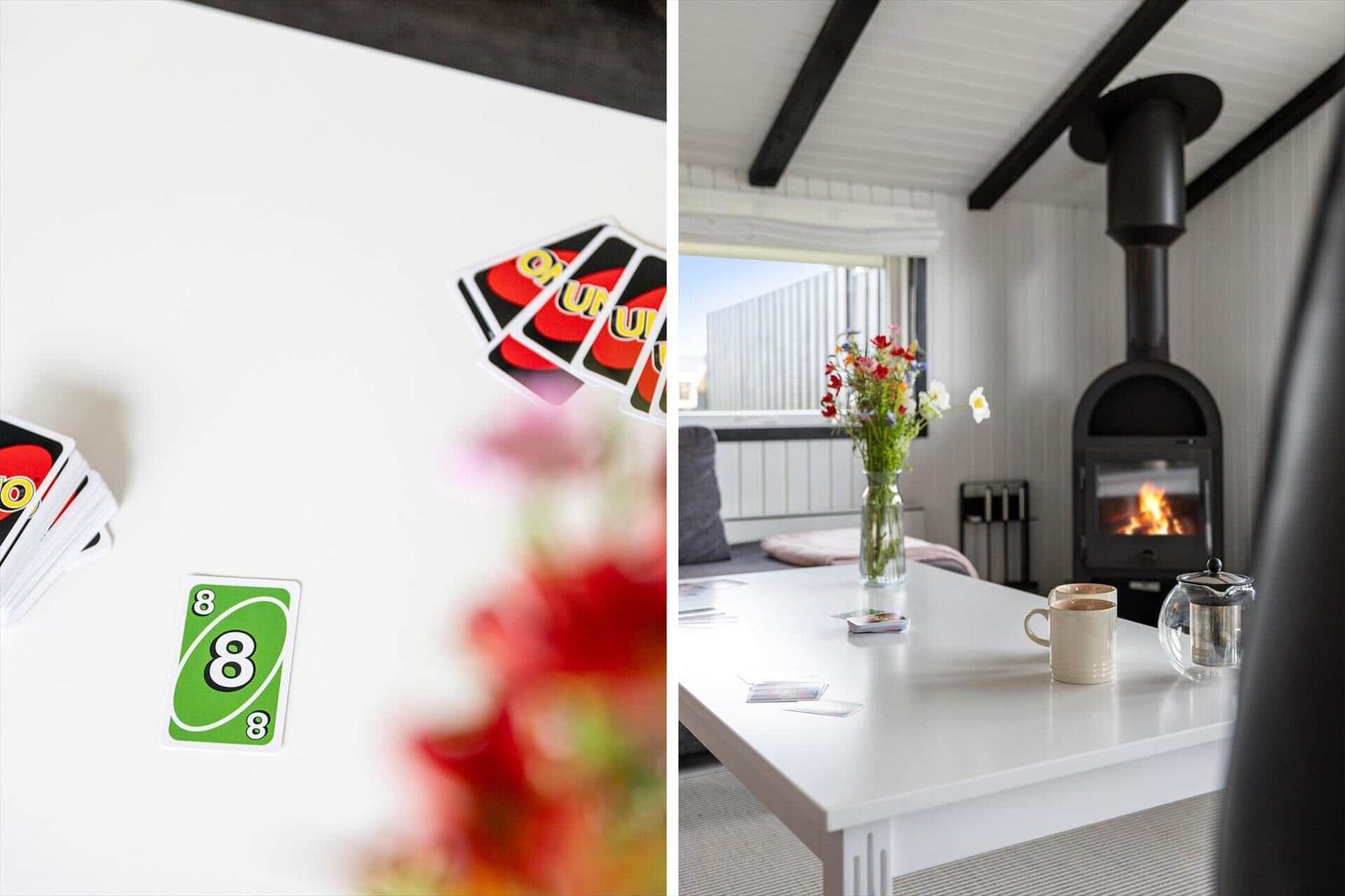 Tisch mit Karten und Blumen, Kaminofen mit brennendem Feuer im Hintergrund.