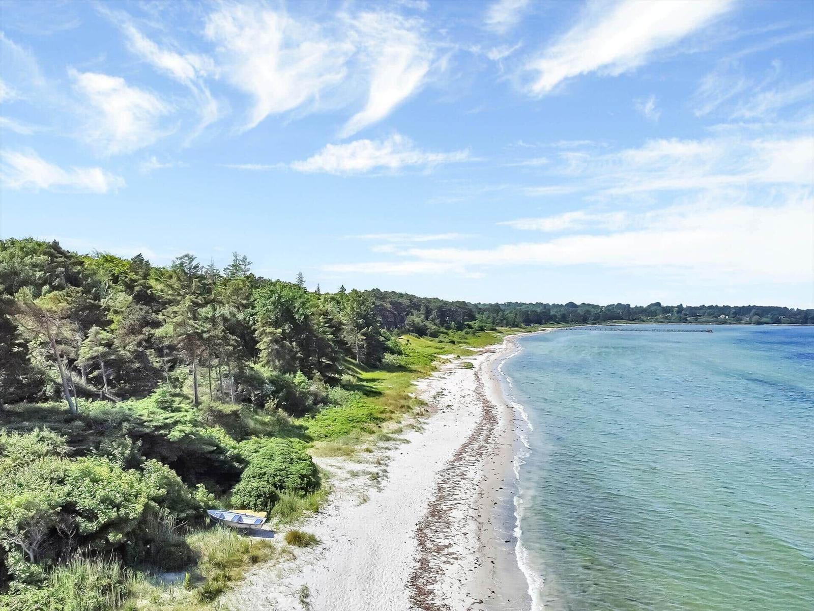 Beach with sand and green areas, small boat rests on the shore.
