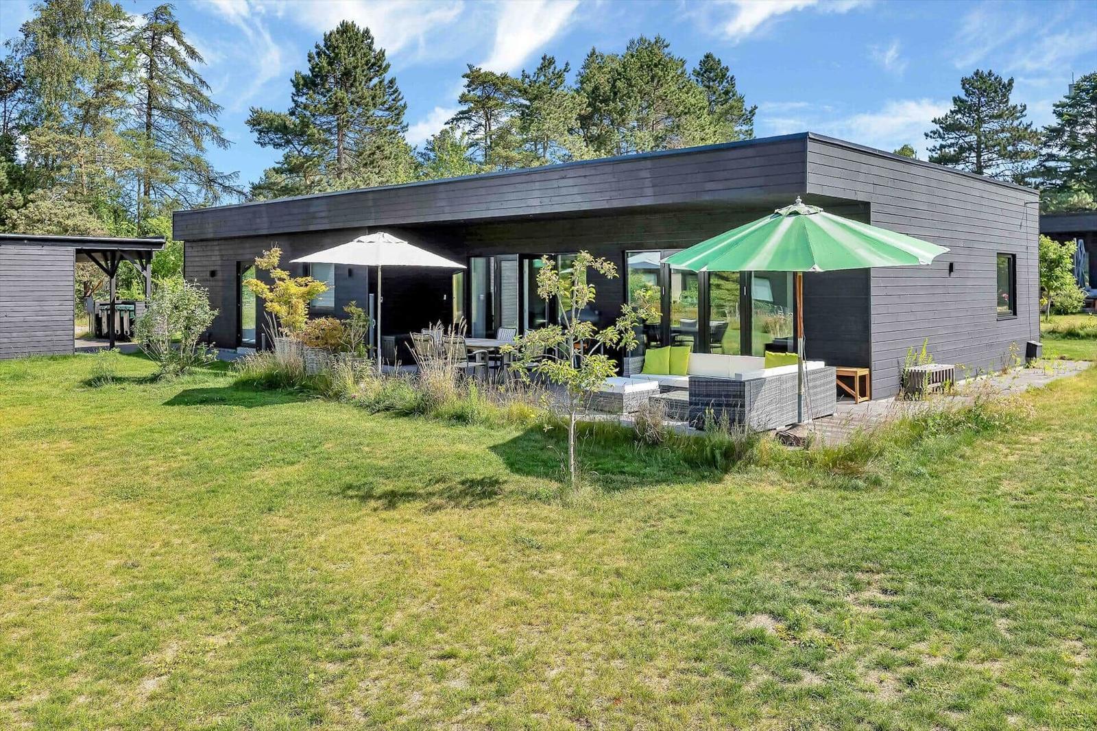 Modern villa with garden, terrace, and green umbrellas.