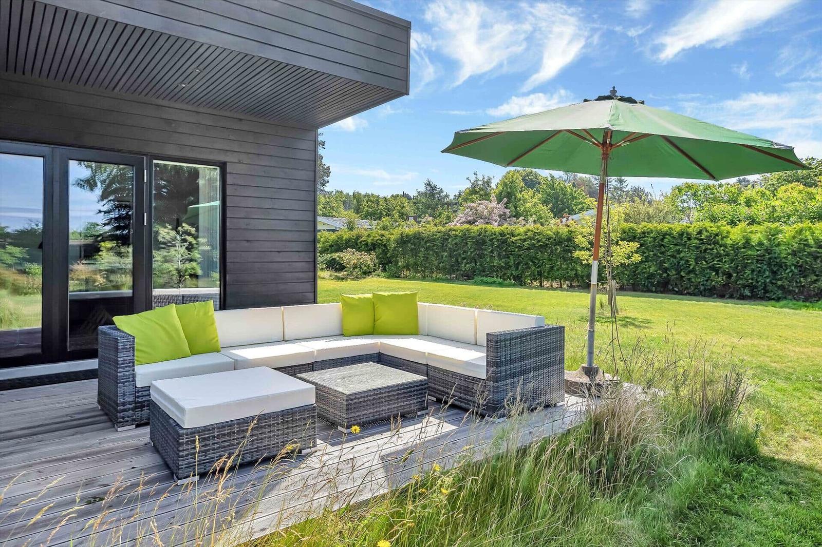 Deck with seating, umbrella, and view of green lawn.