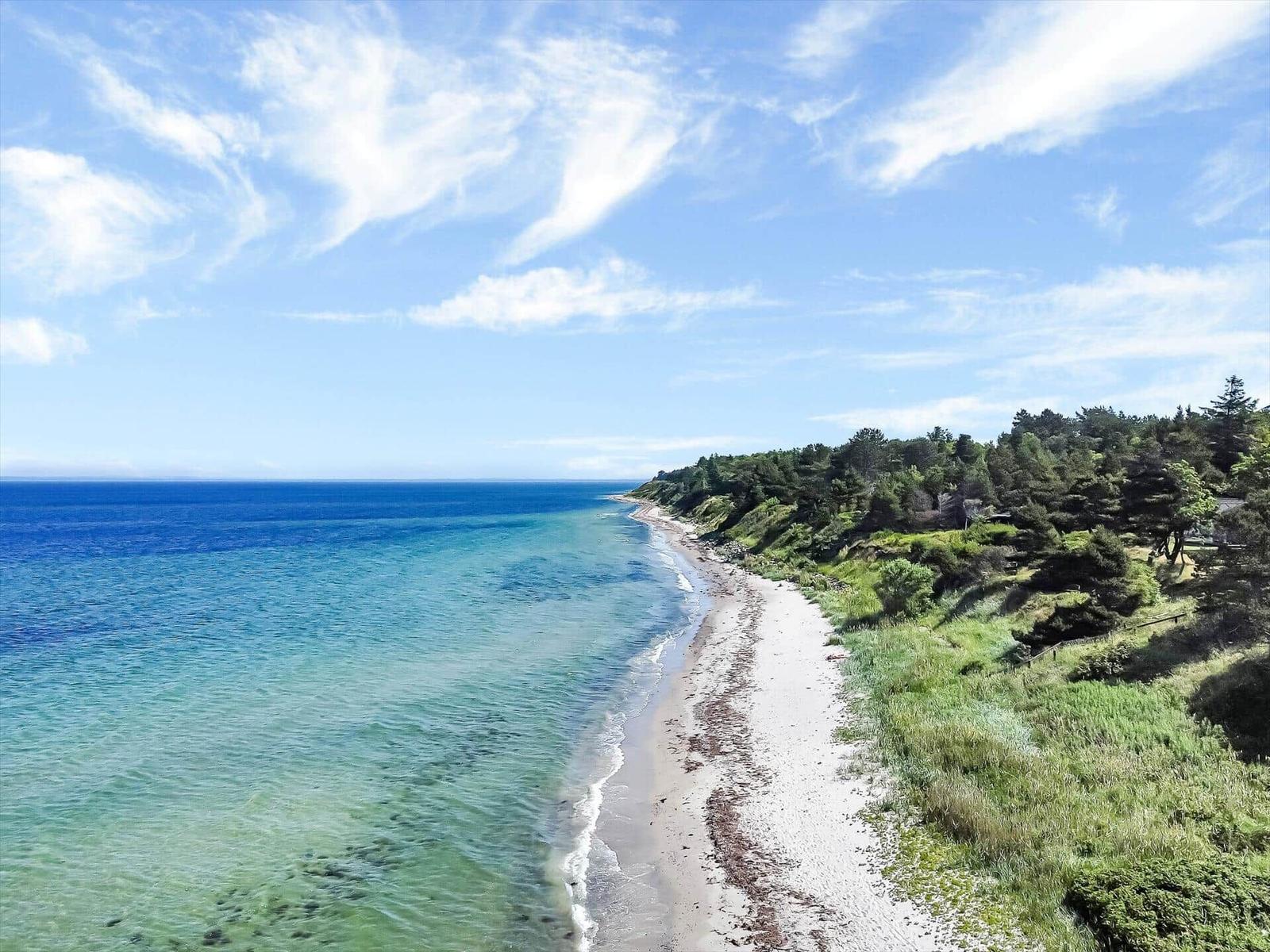 Beach with clear water and green vegetation along the coast.