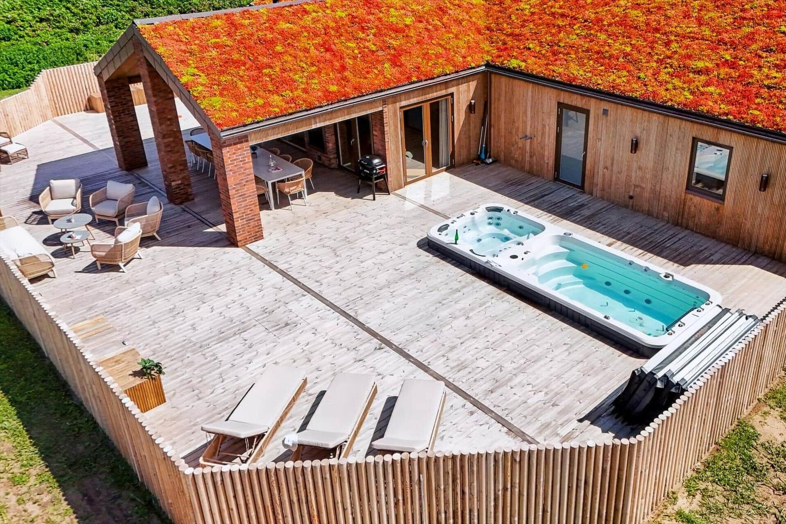 Haus mit begrüntem Dach, Whirlpool und Terrasse mit Sitzgelegenheiten.