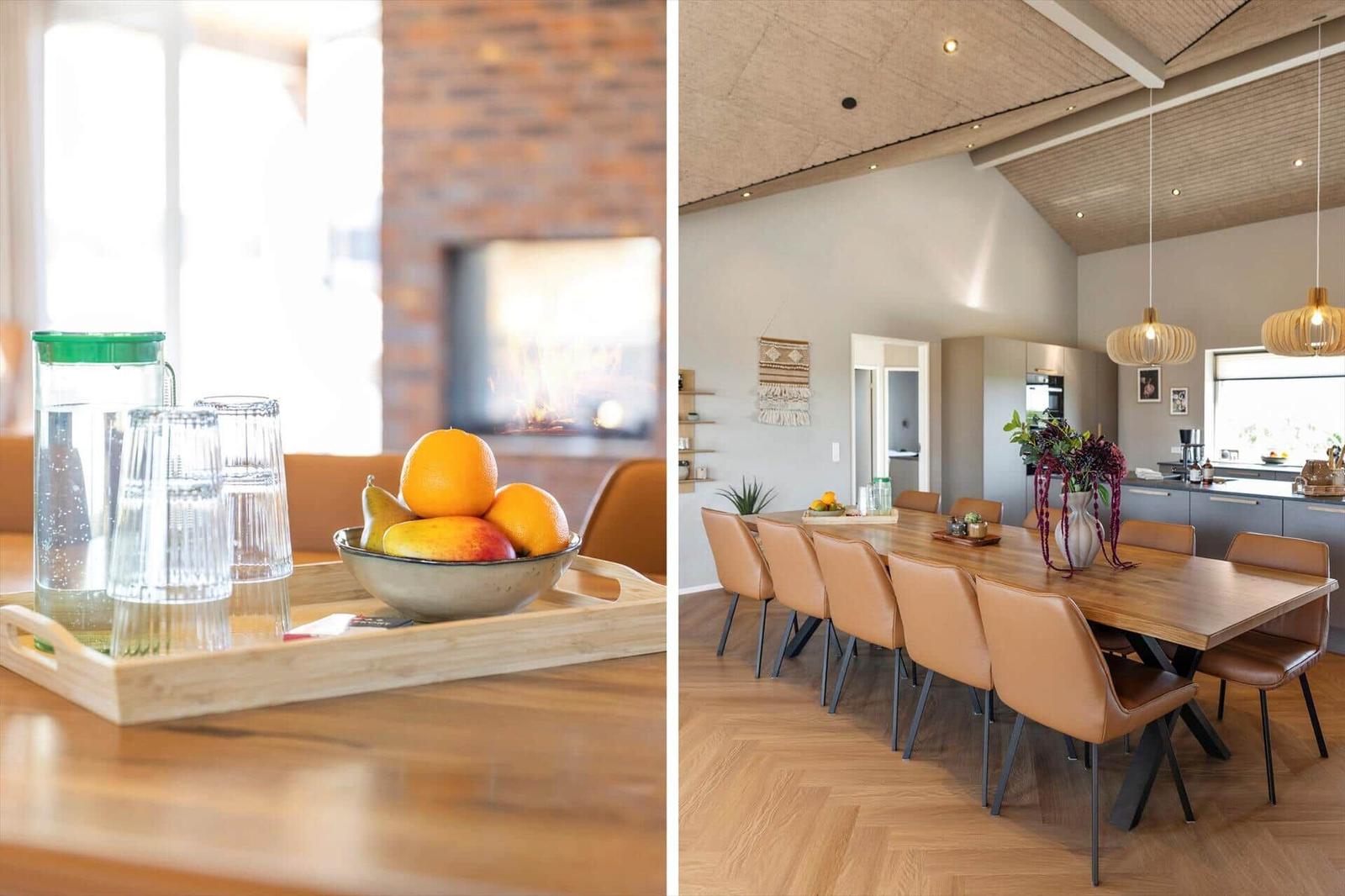 Esszimmer mit Holztisch, Ledersitzen und moderner Beleuchtung. Kamin im Hintergrund. Fruchttablett im Vordergrund.