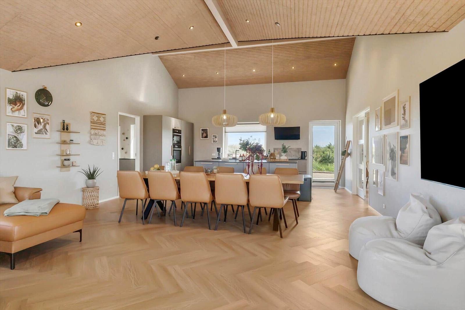Großes Wohn- und Esszimmer mit Holzboden, Essbereich und Küche im Hintergrund.