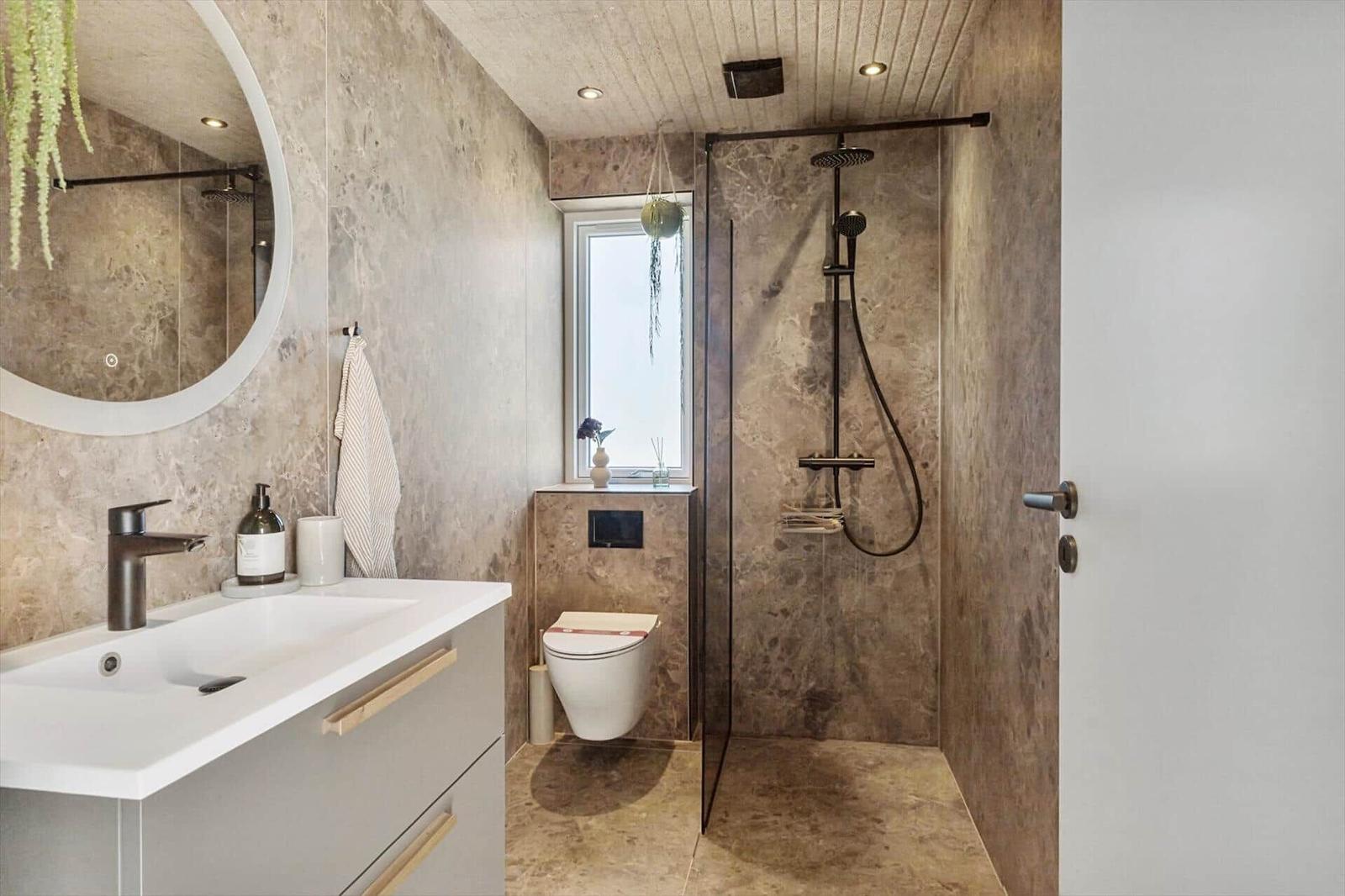 Badezimmer mit Dusche, Waschbecken und Toilette. Marmorwände und -boden.
