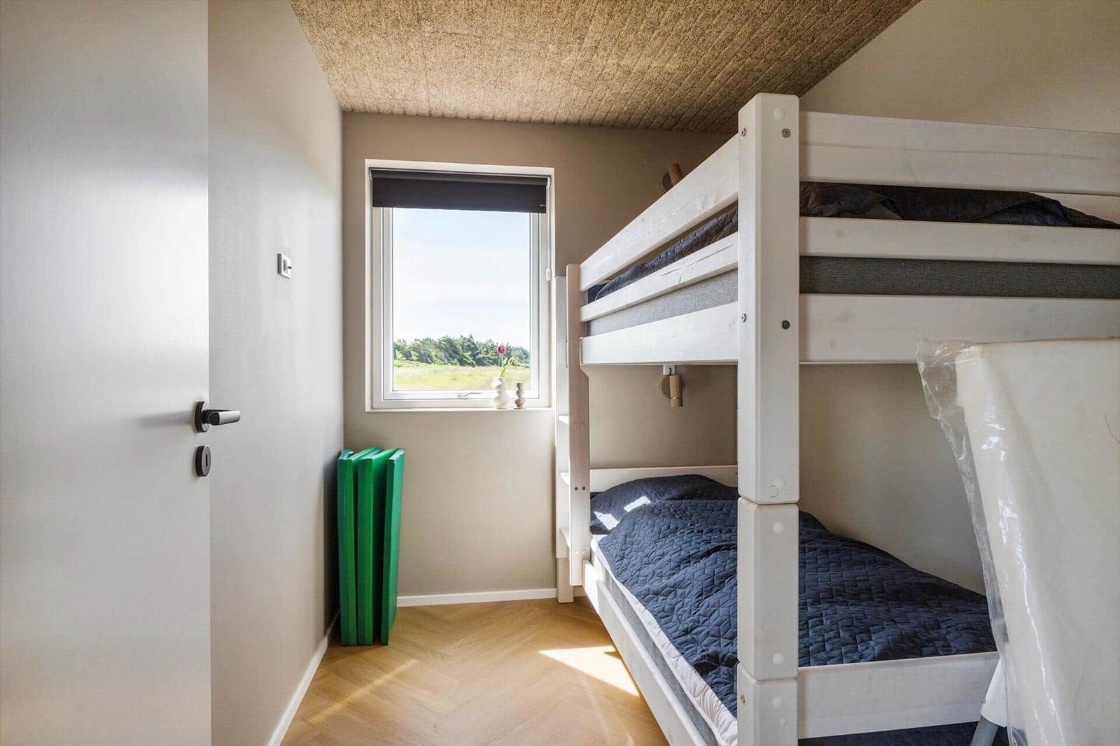Zimmer mit Doppelstockbett, Fenster und Holzboden.