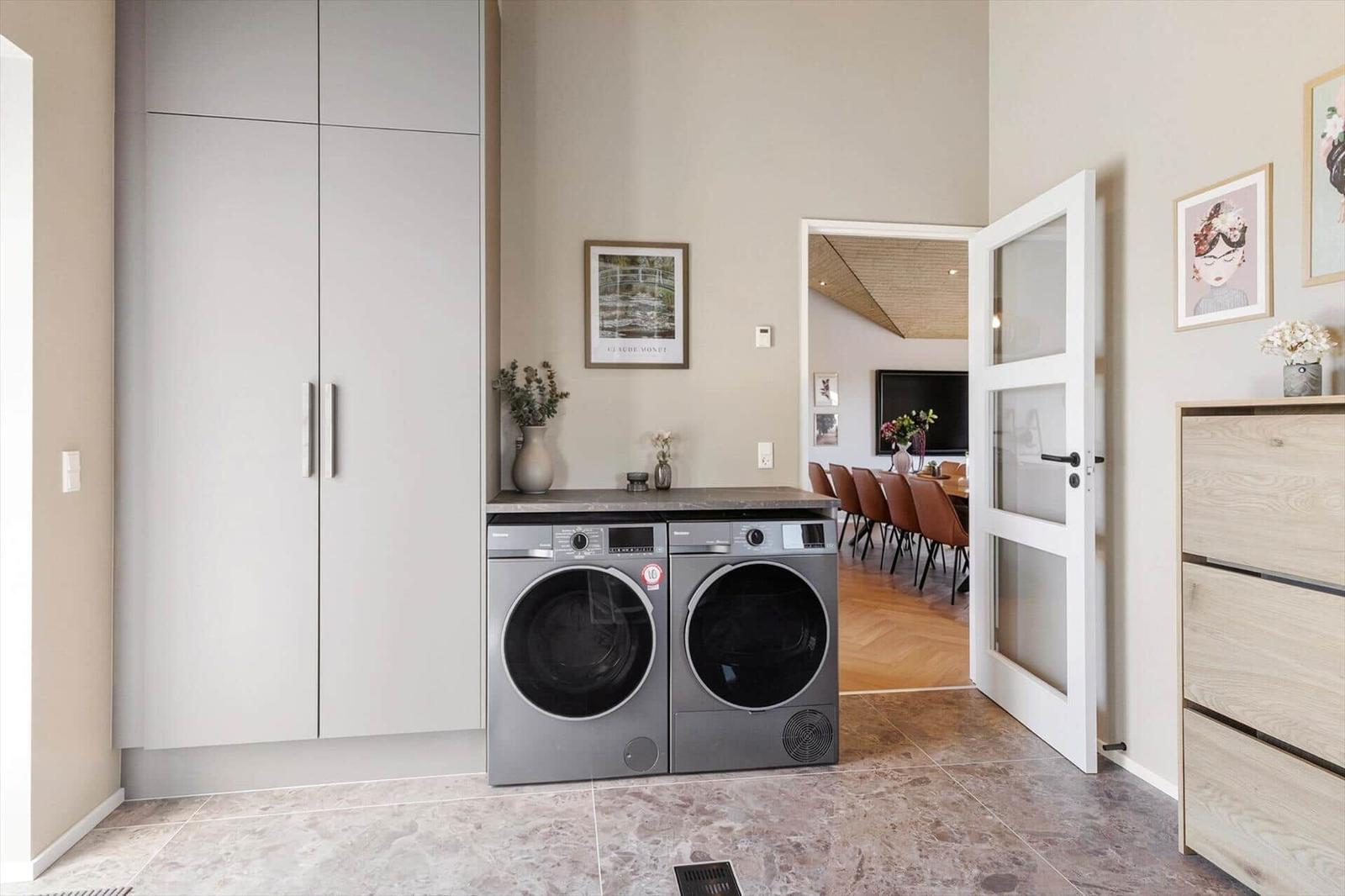Wohnraum mit Waschmaschine und Trockner, Tür führt in Esszimmer.