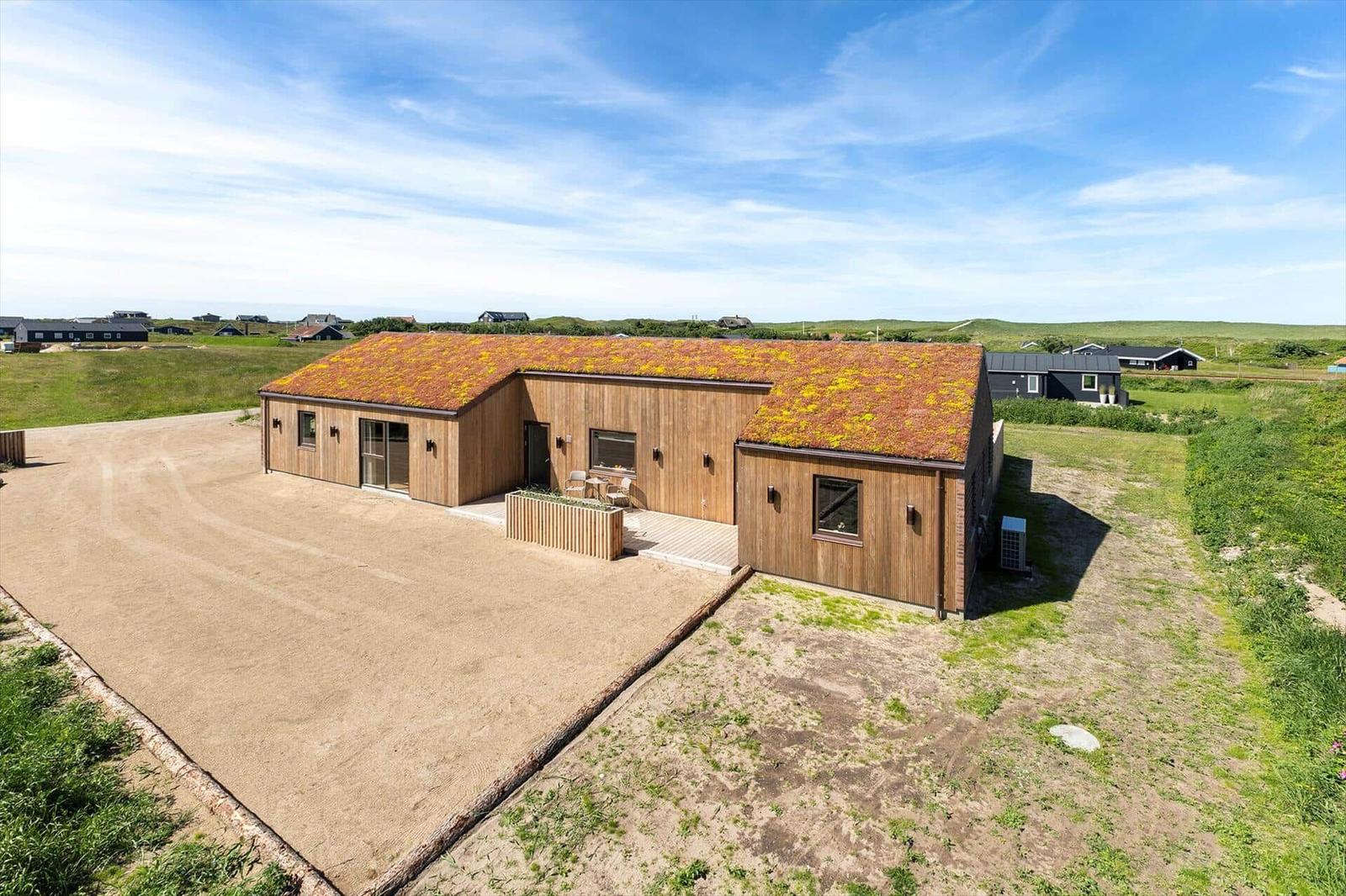 Moderne Holzhütte mit grüner Dachbegrünung und Terrasse im Freien.