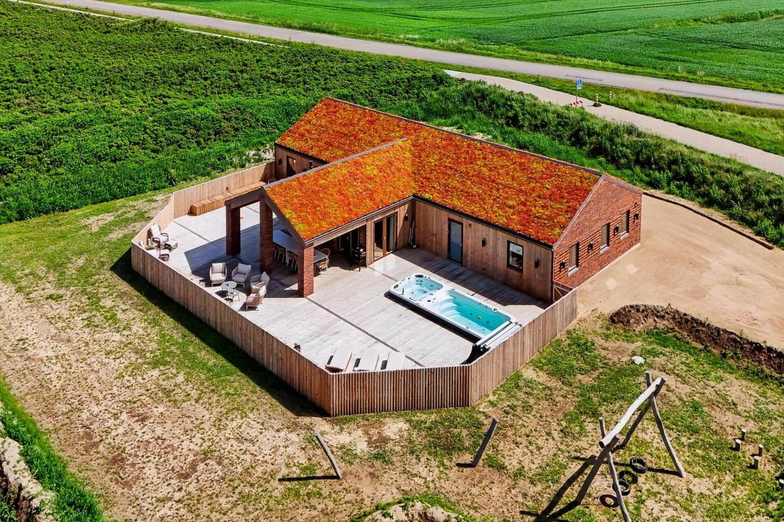 Moderne Villa mit grüner Dachdeckung, Terrasse und Whirlpool im ländlichen Umfeld.