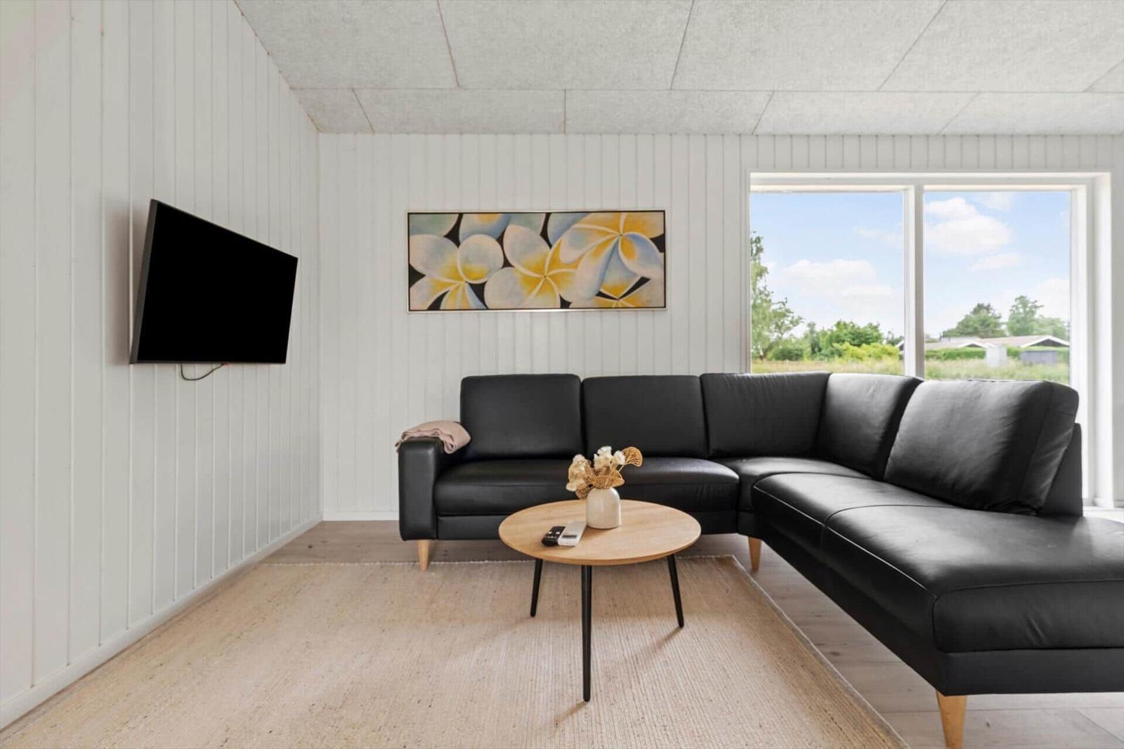 Ein Wohnzimmer mit schwarzem Sofa, runden Tisch und Wandbild.