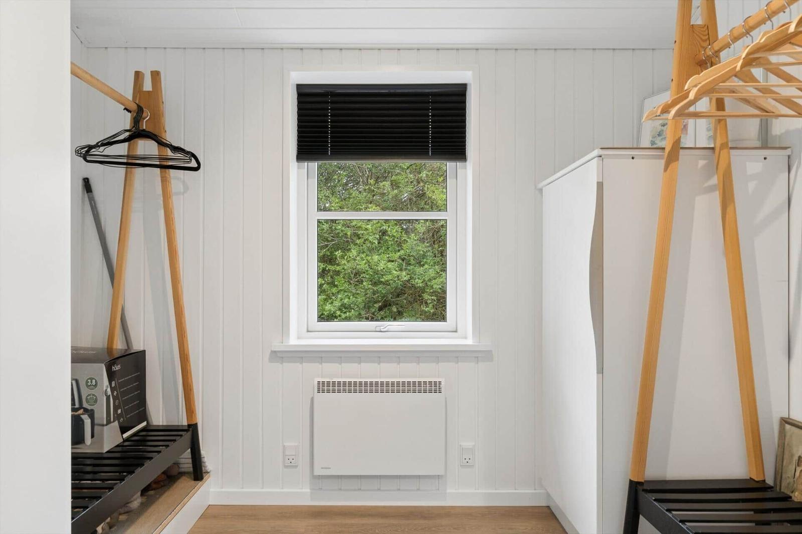 Zimmer mit Fenster, Gardine, Heizkörper und Kleiderständer