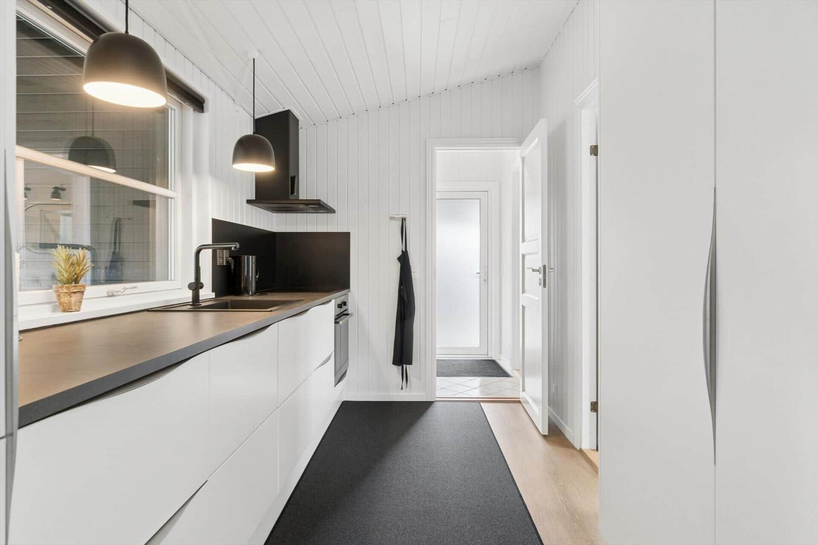 Moderne Küche mit weißen Schränken, dunklem Arbeitsplatz und Fenster mit Pflanze.