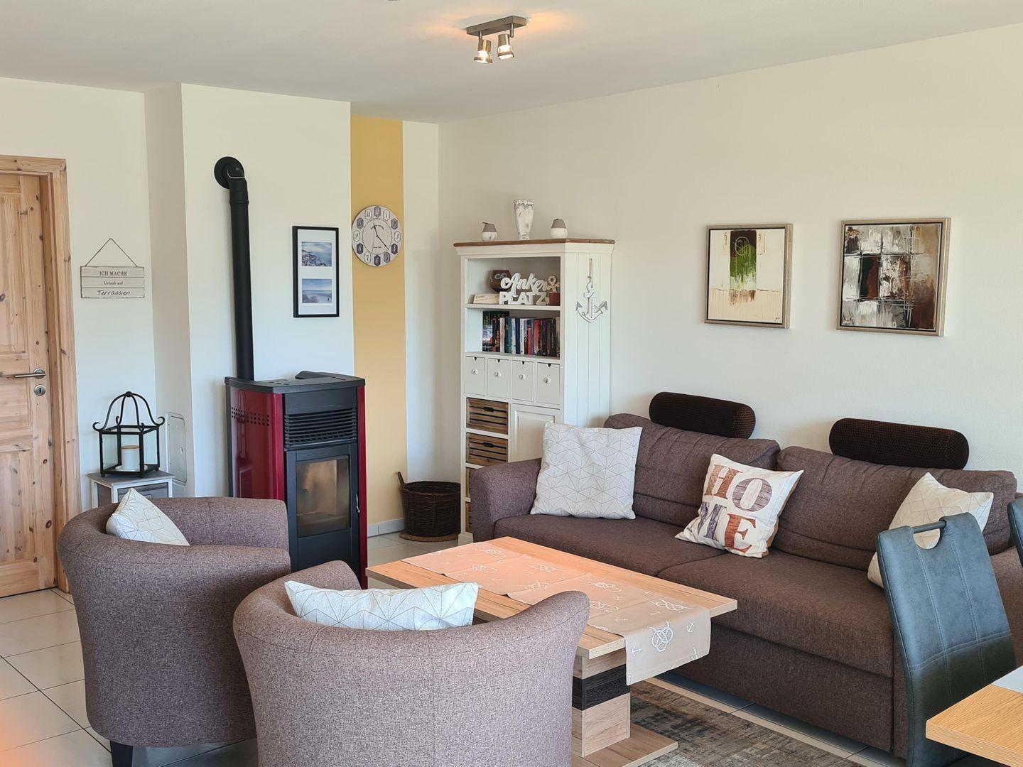 Wohnzimmer mit Sofa, Sesseln, Kamin und Bücherregal.