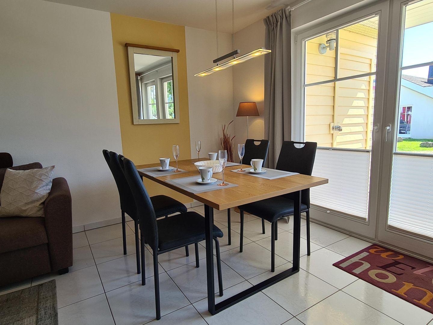 Essbereich mit Tisch, Stühlen und Fenster zur Terrasse.