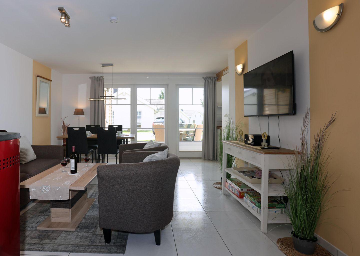 Wohn- und Essbereich mit Sofa, Fernseher und Blick auf Balkon.